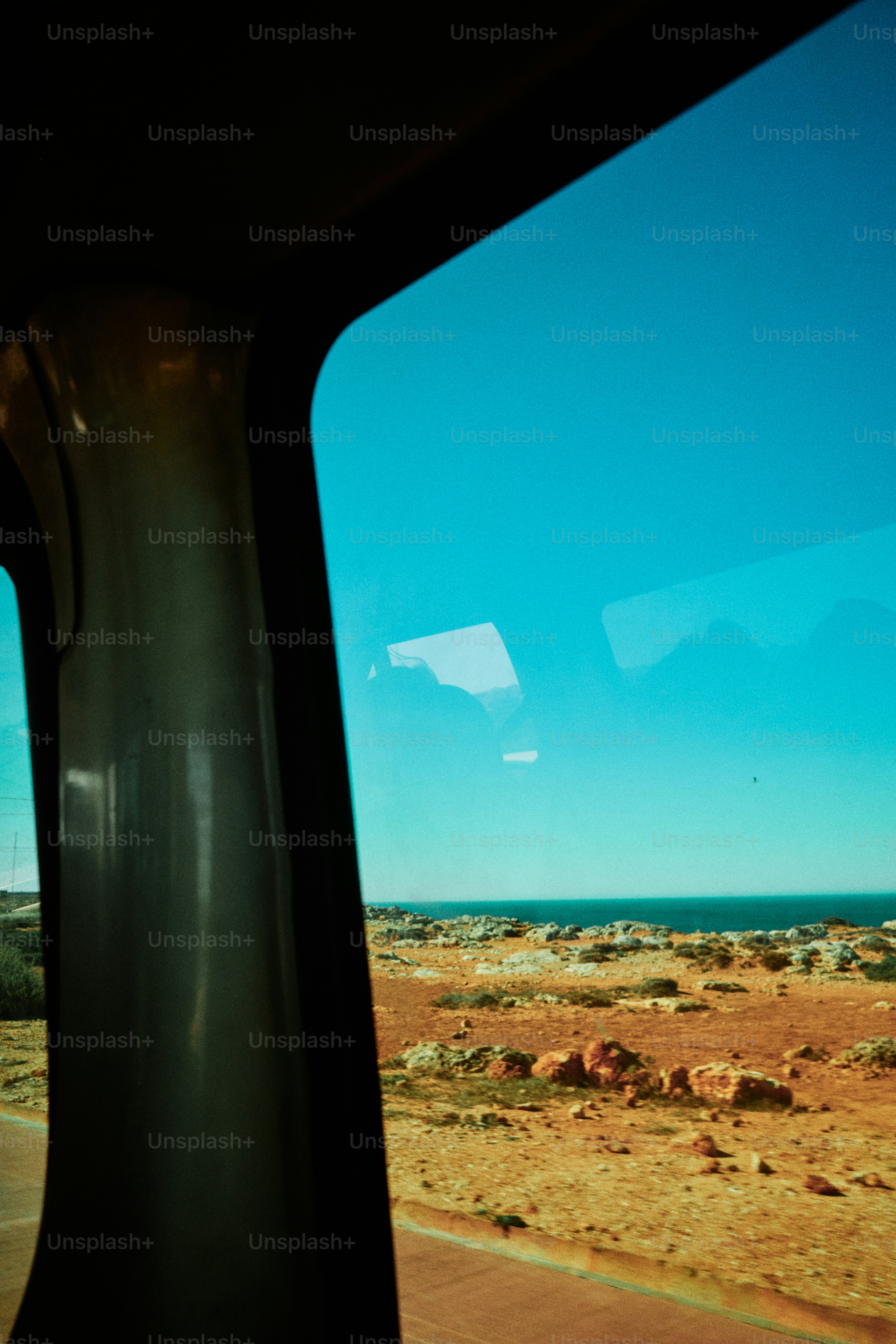 Blick auf trockene Landschaft und Ozean aus dem Fahrzeugfenster