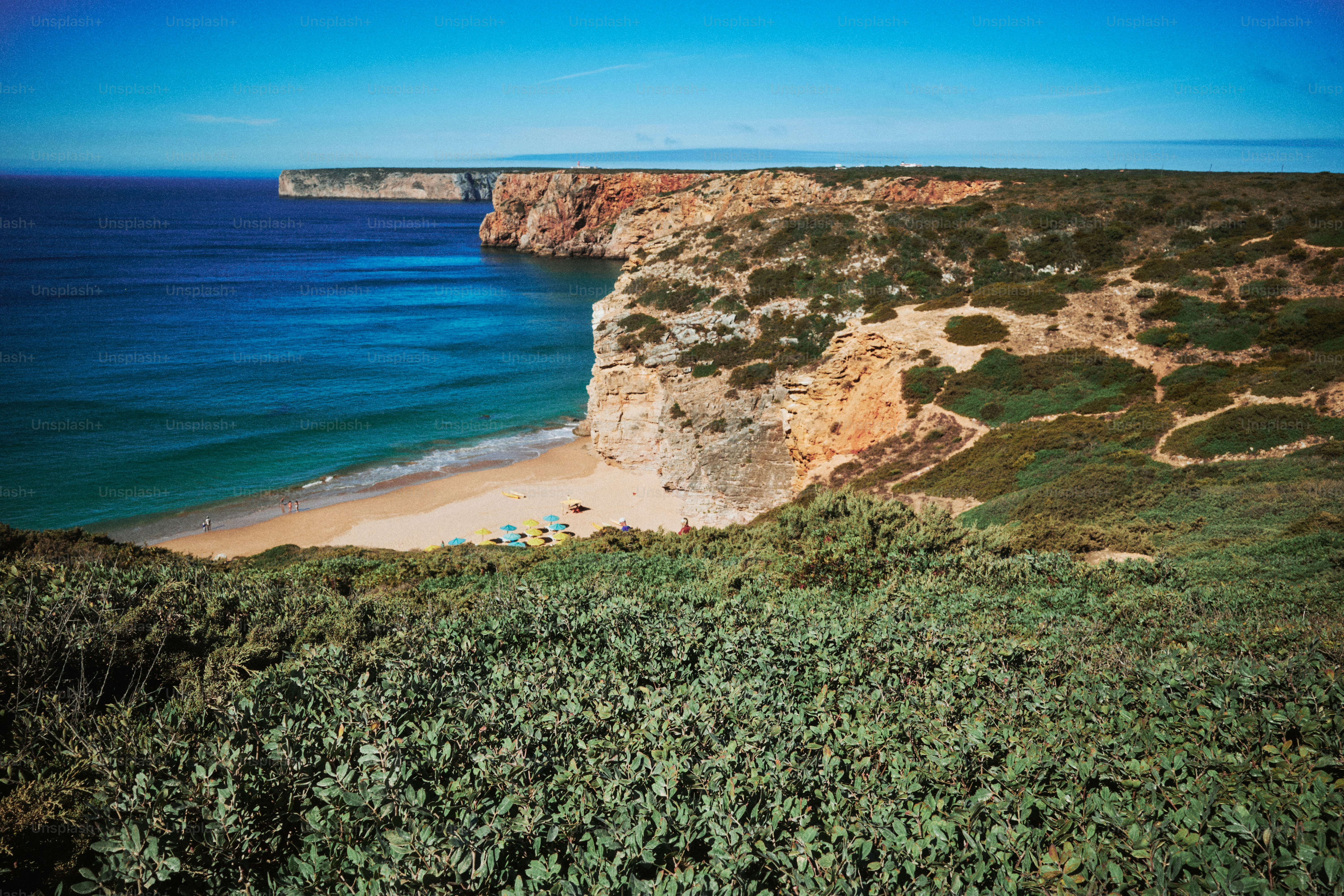 Acantilados costeros con vistas a una playa de arena y un océano azul.
