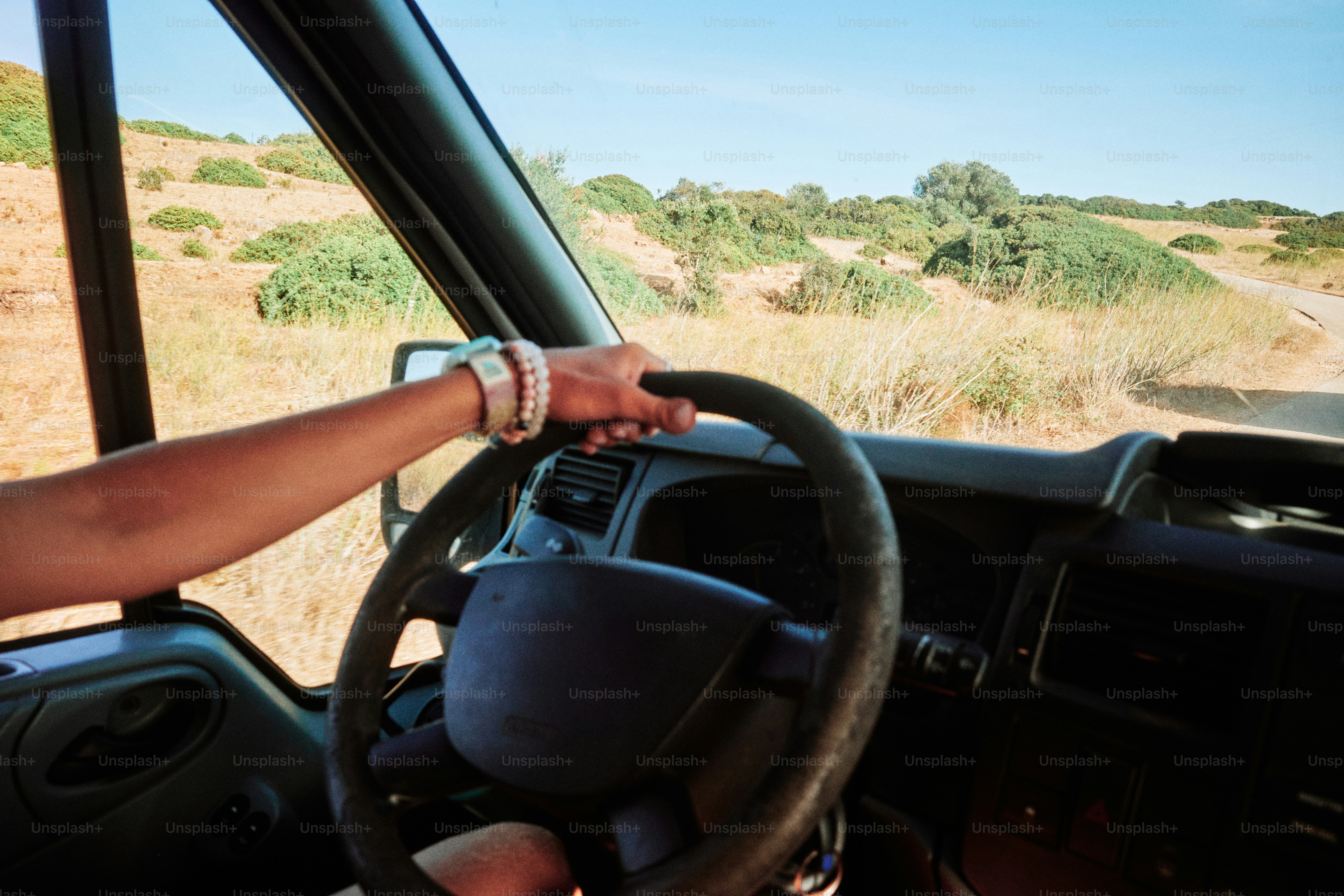 Conducir con la mano en el volante en un día soleado.