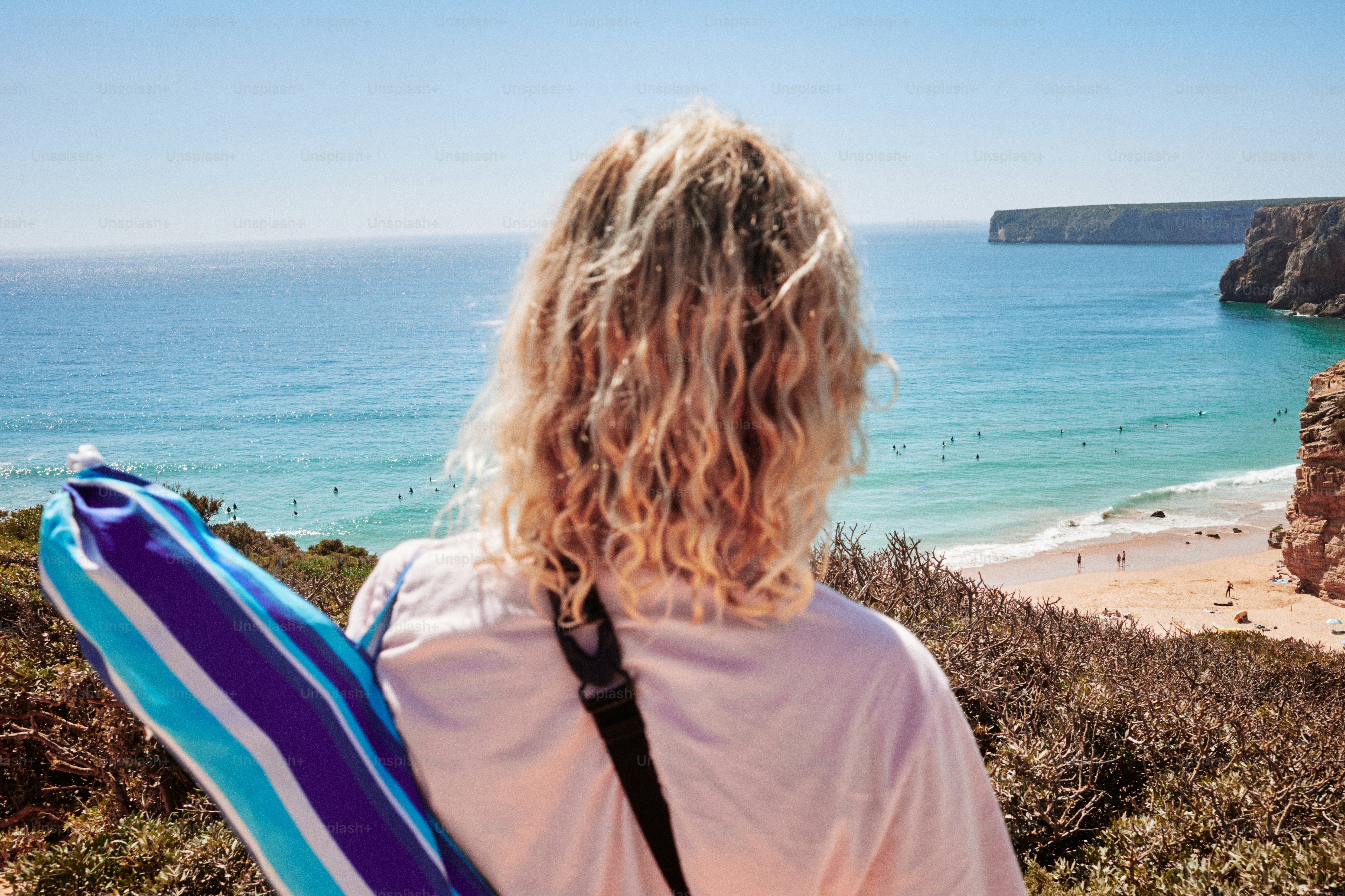 Frau mit Strandstuhl mit Blick auf Ozean und Strand