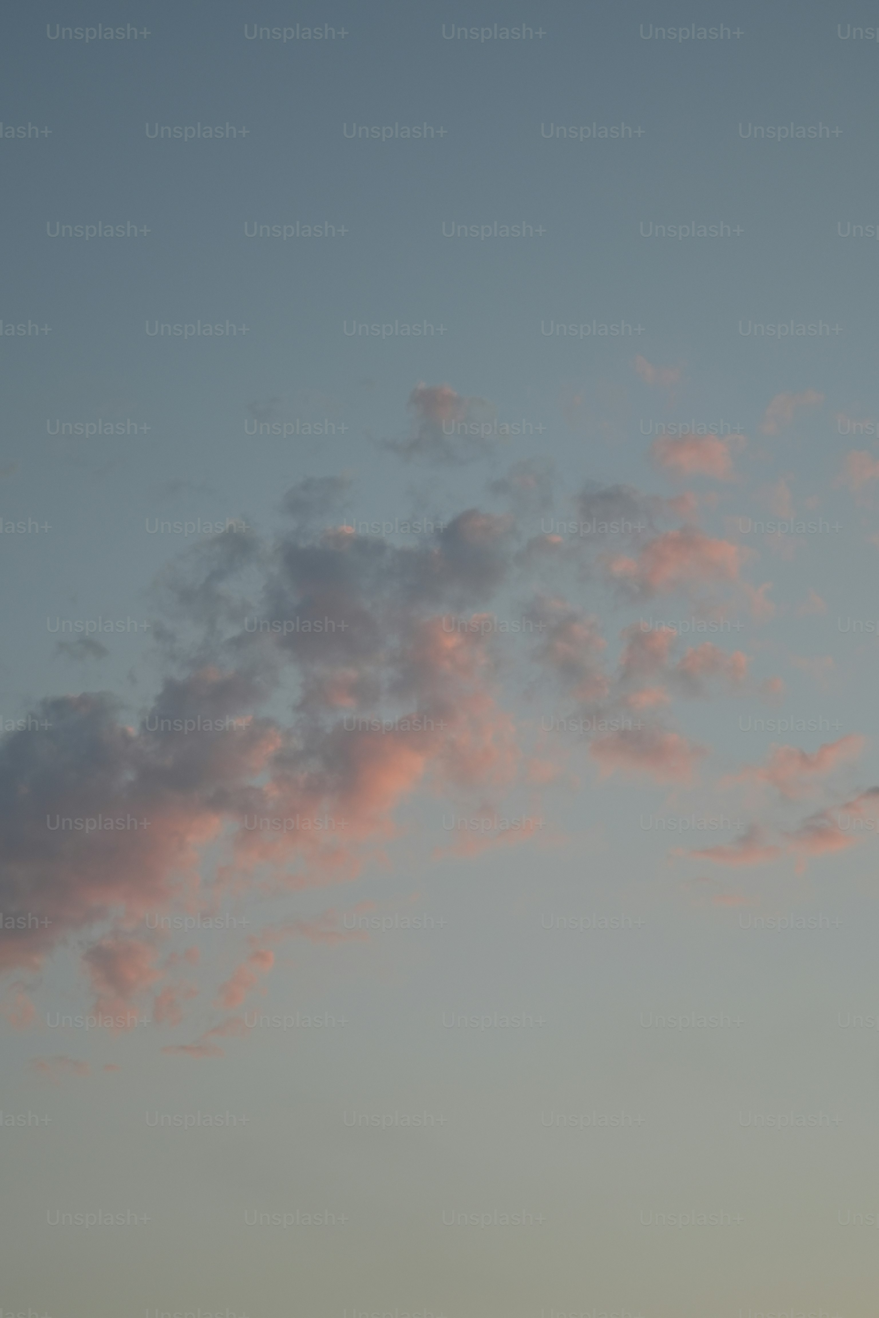 Soft pink clouds float in a pale blue sky