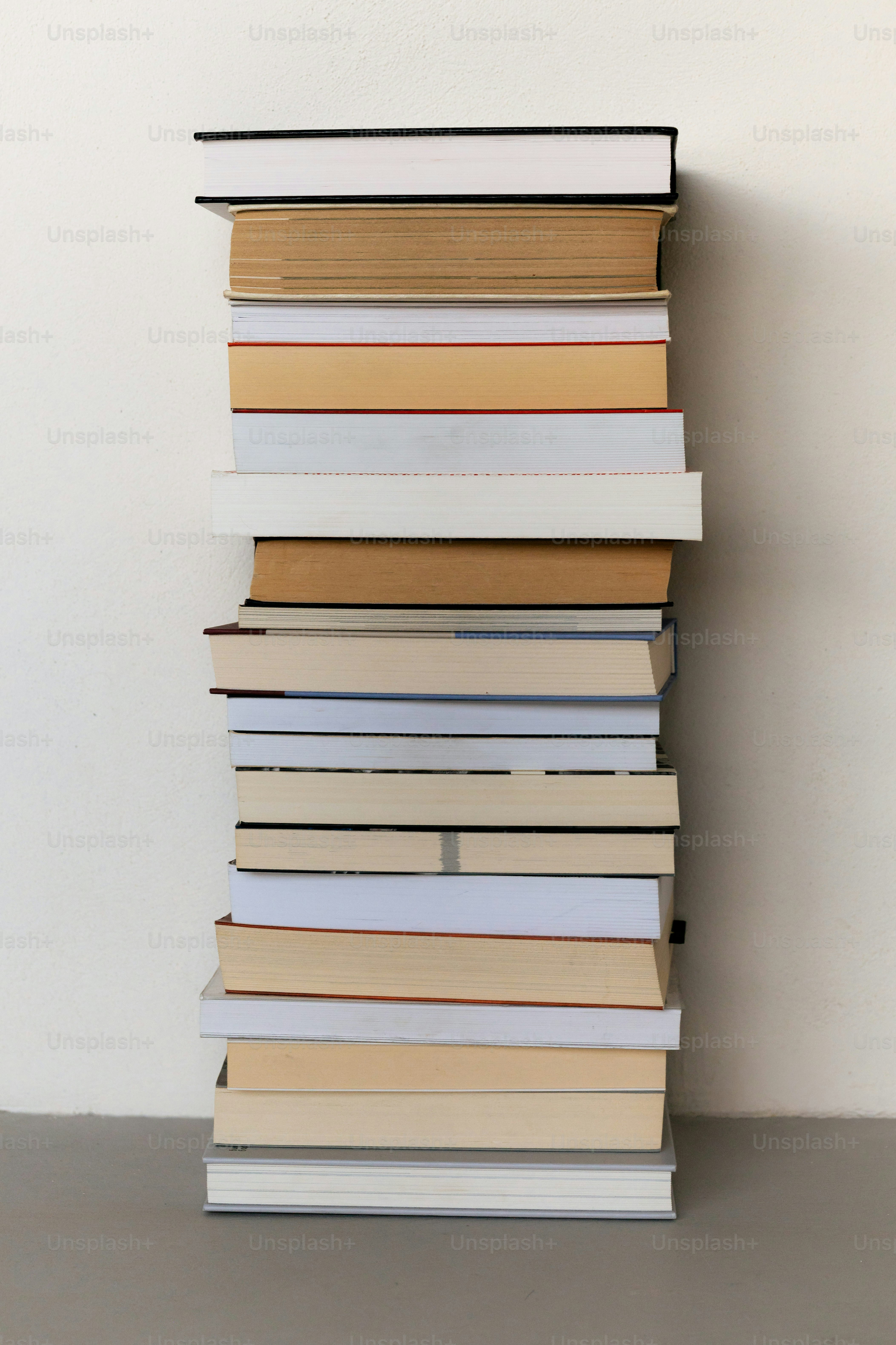 A tall stack of assorted books on a shelf.