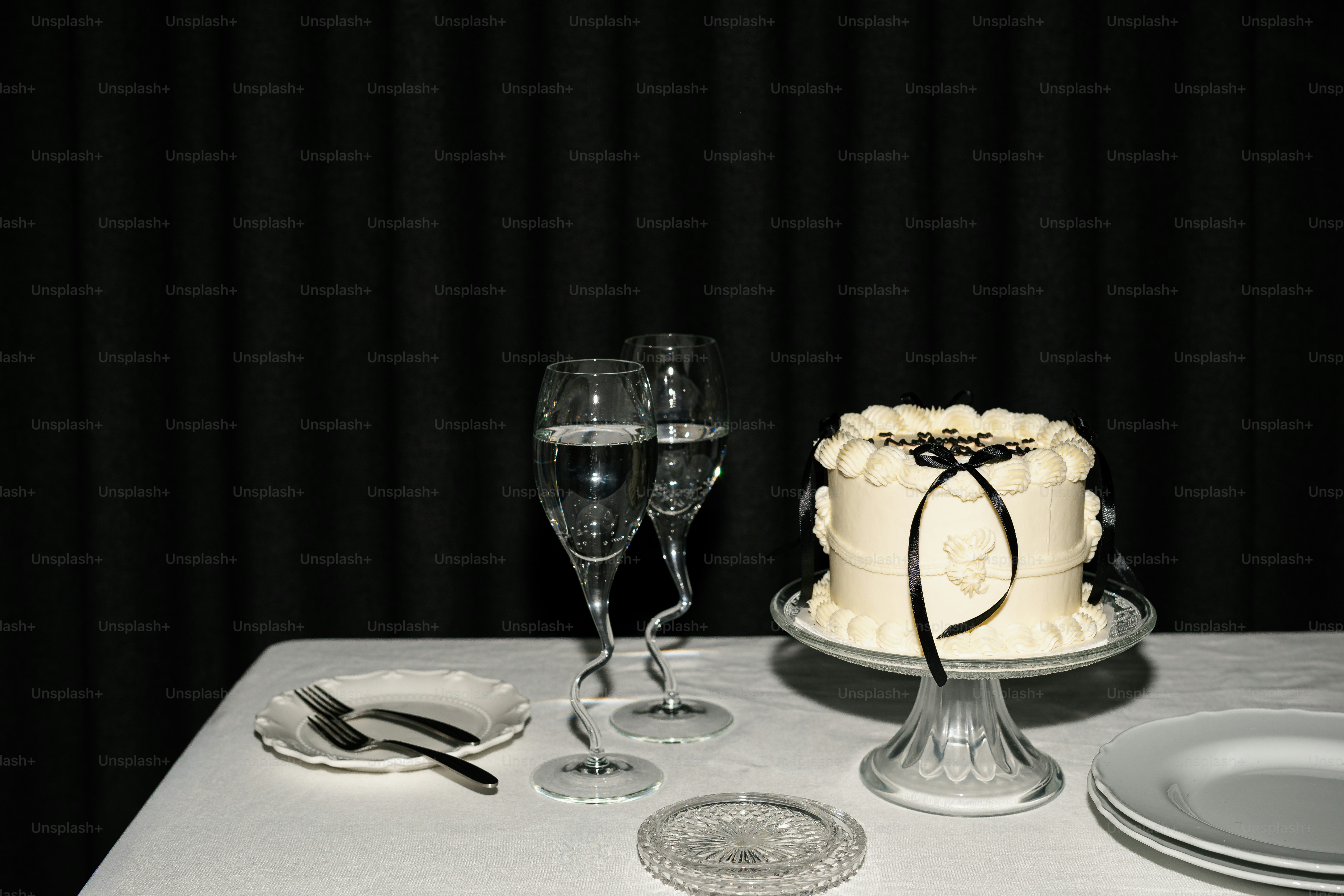 Ein kleiner weißer Kuchen mit Band und zwei Champagnergläsern