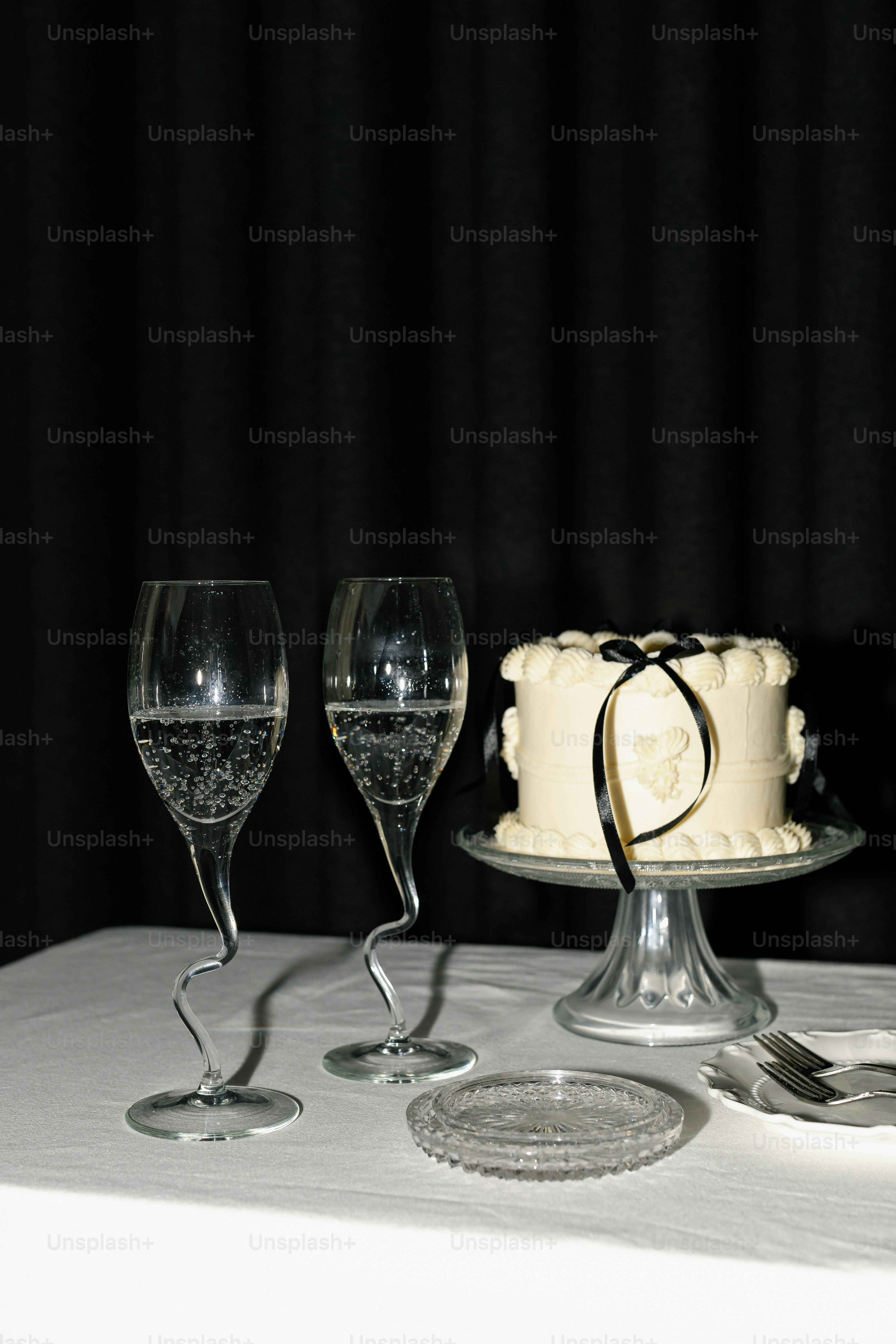 Two champagne glasses beside a small white cake