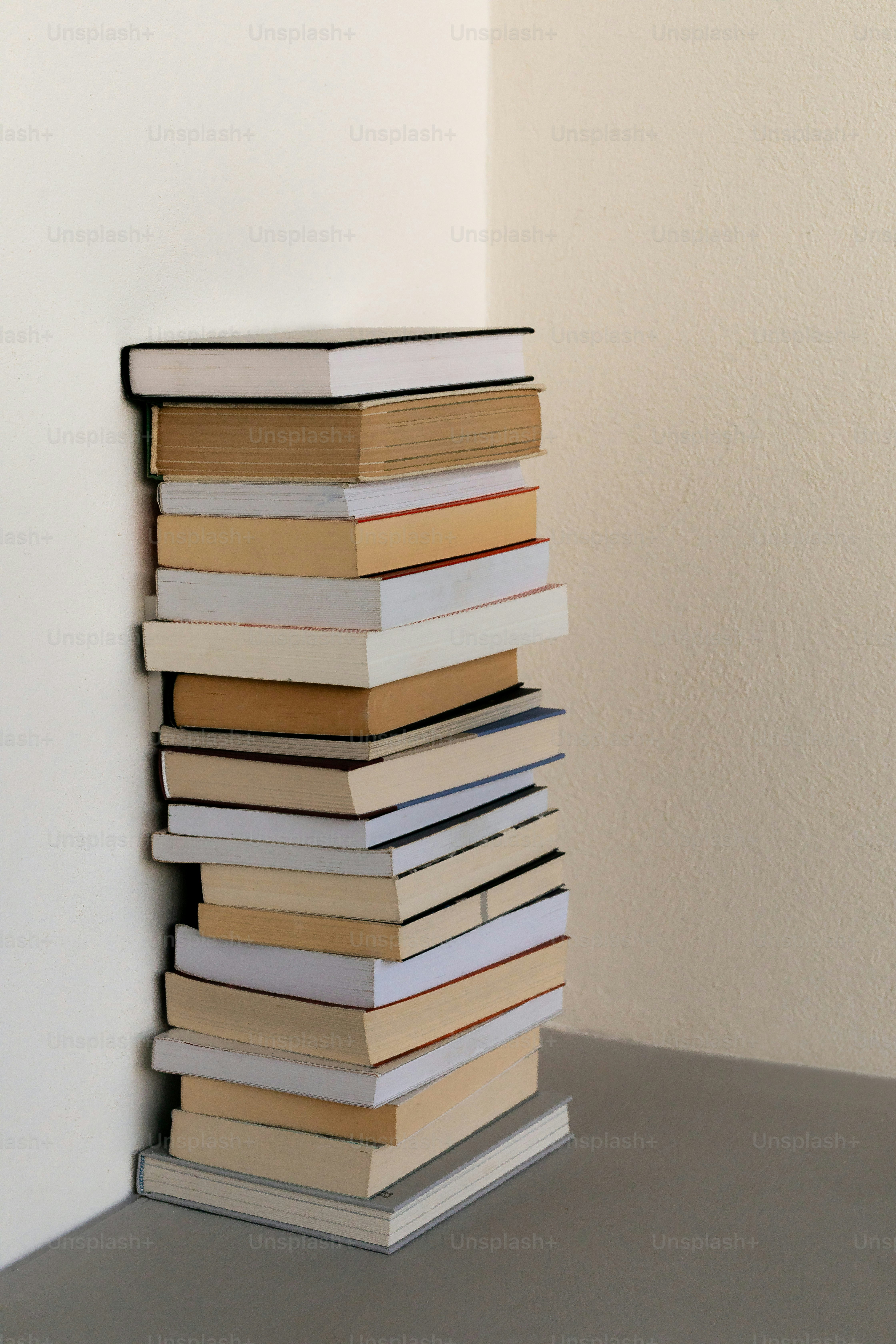A tall stack of books leaning in a corner.