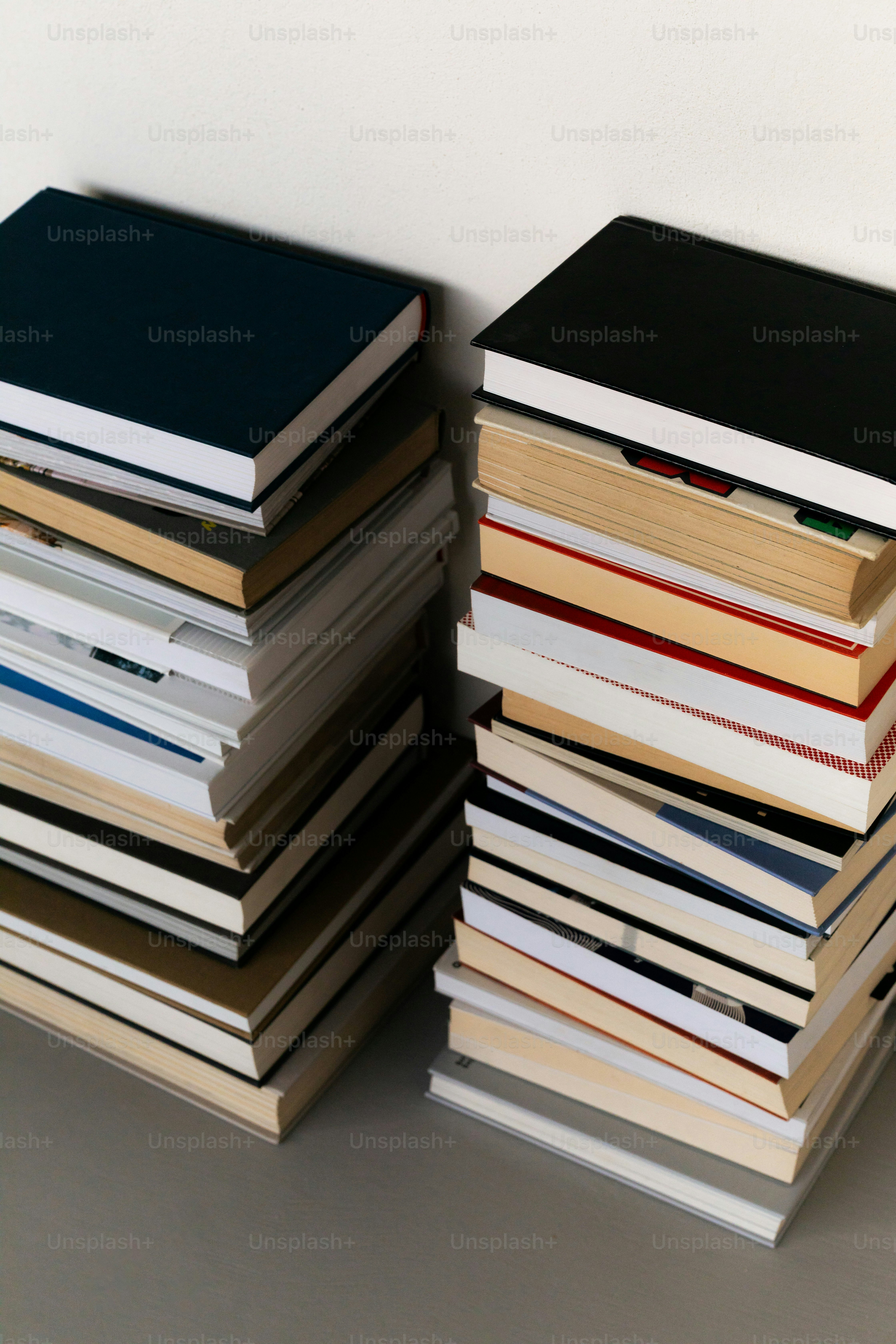 Zwei Stapel Bücher an einer Wand.