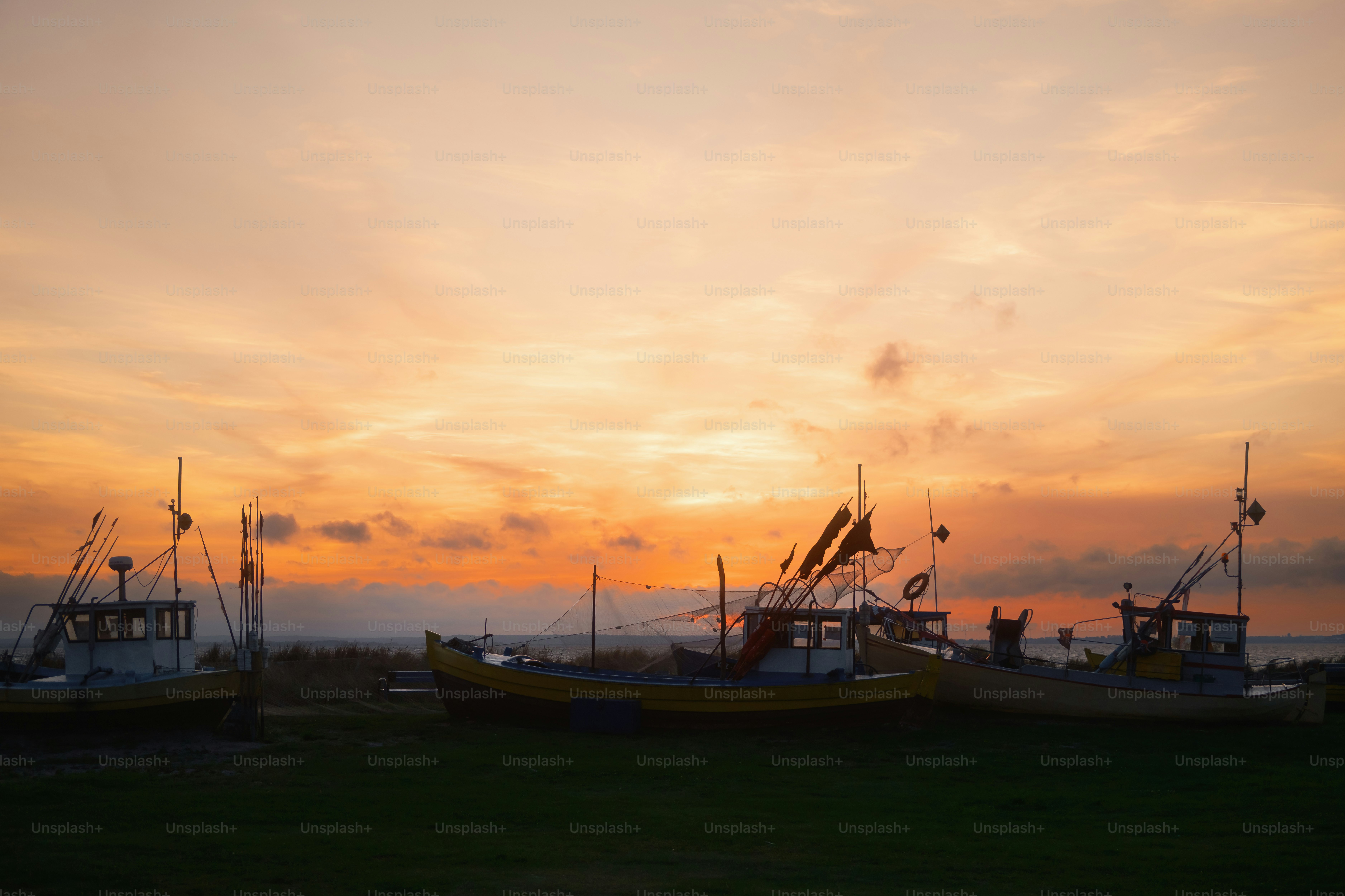 Fishing boats docked at sunset with orange sky photo – Image on Unsplash