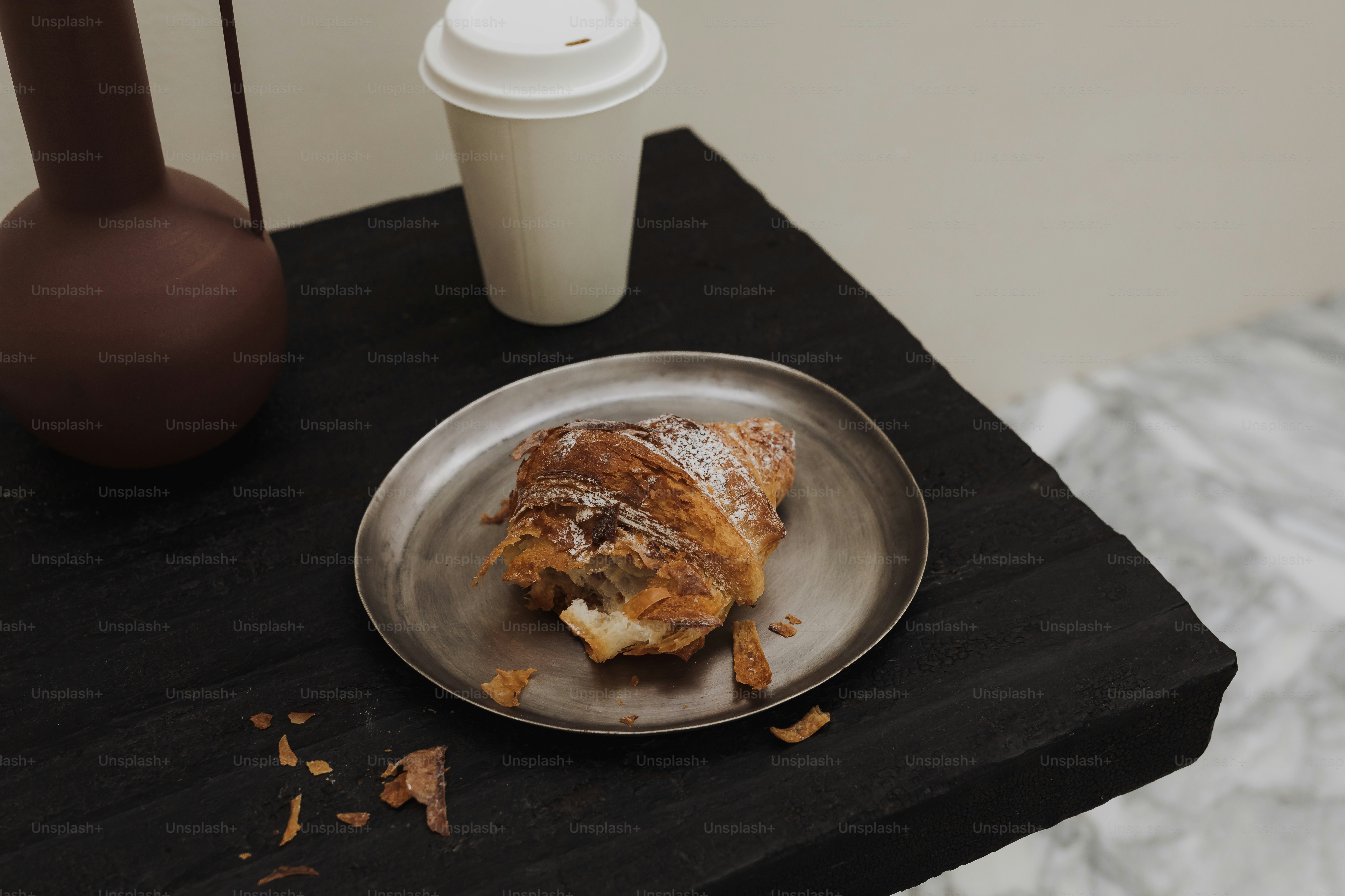 Croissant auf einem Teller mit einer Kaffeetasse