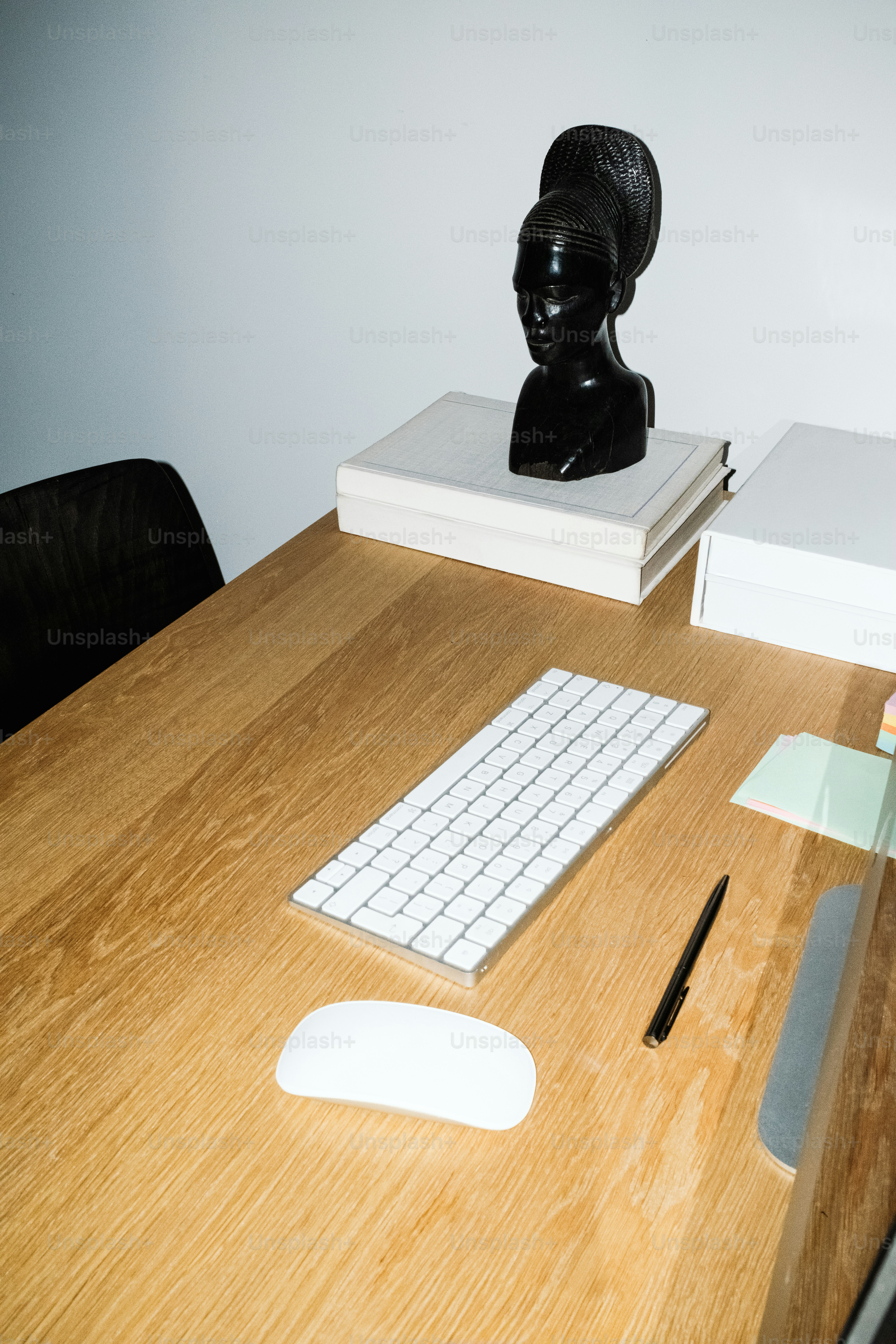 Wooden desk with keyboard, mouse, and bust.