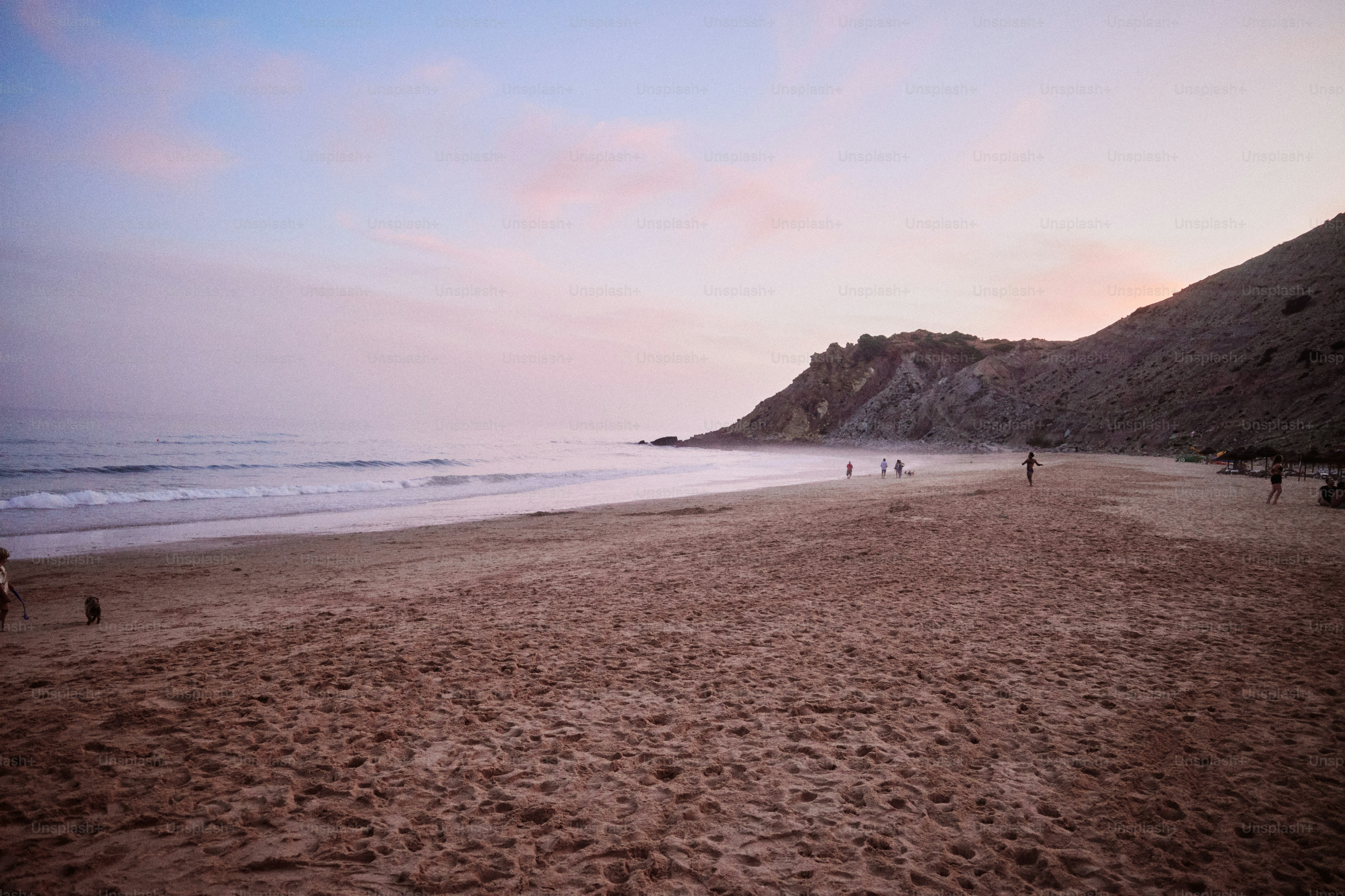 Playa con suaves olas al anochecer y figuras lejanas