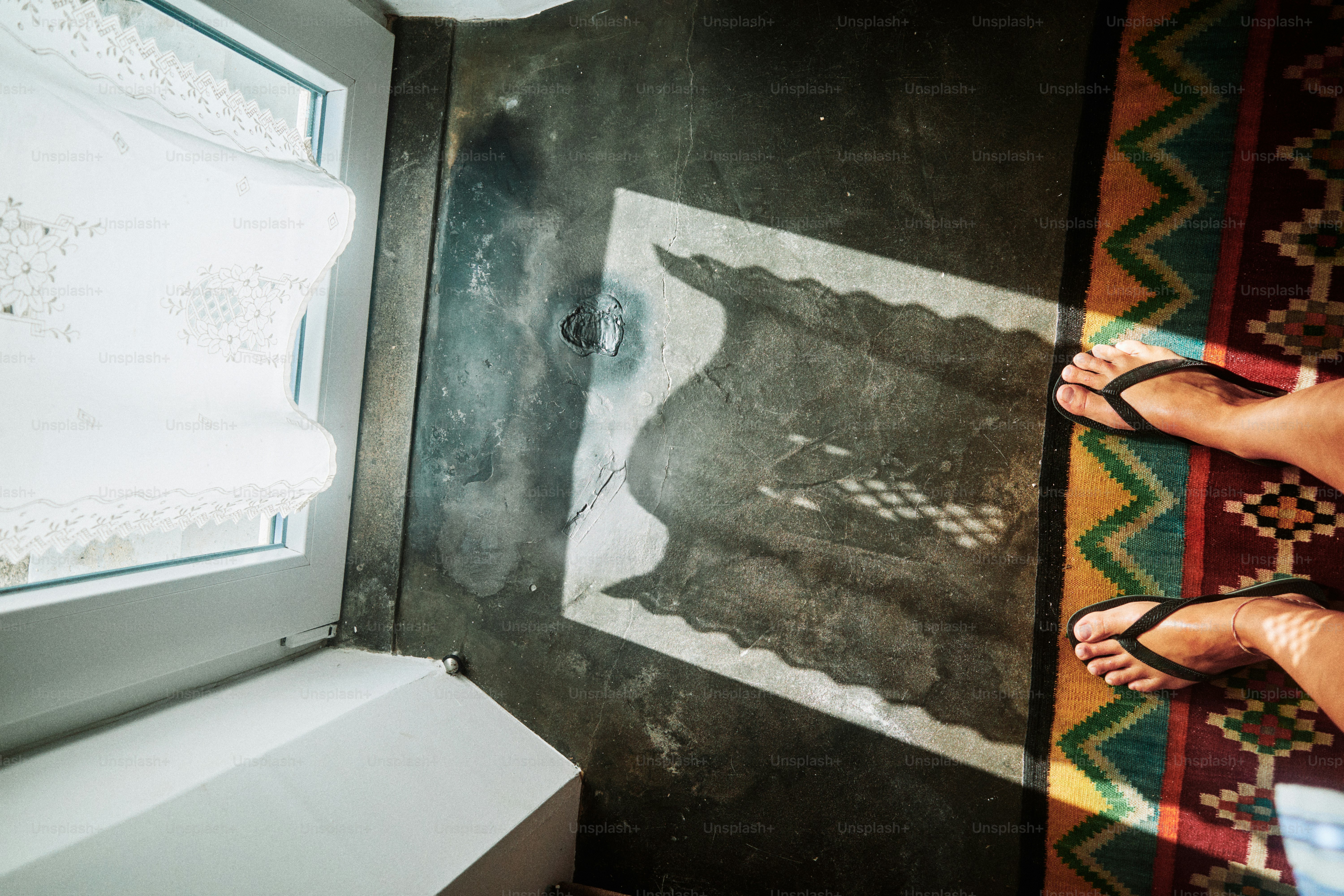 La luz del sol entra a través de una cortina translúcida sobre una alfombra estampada.