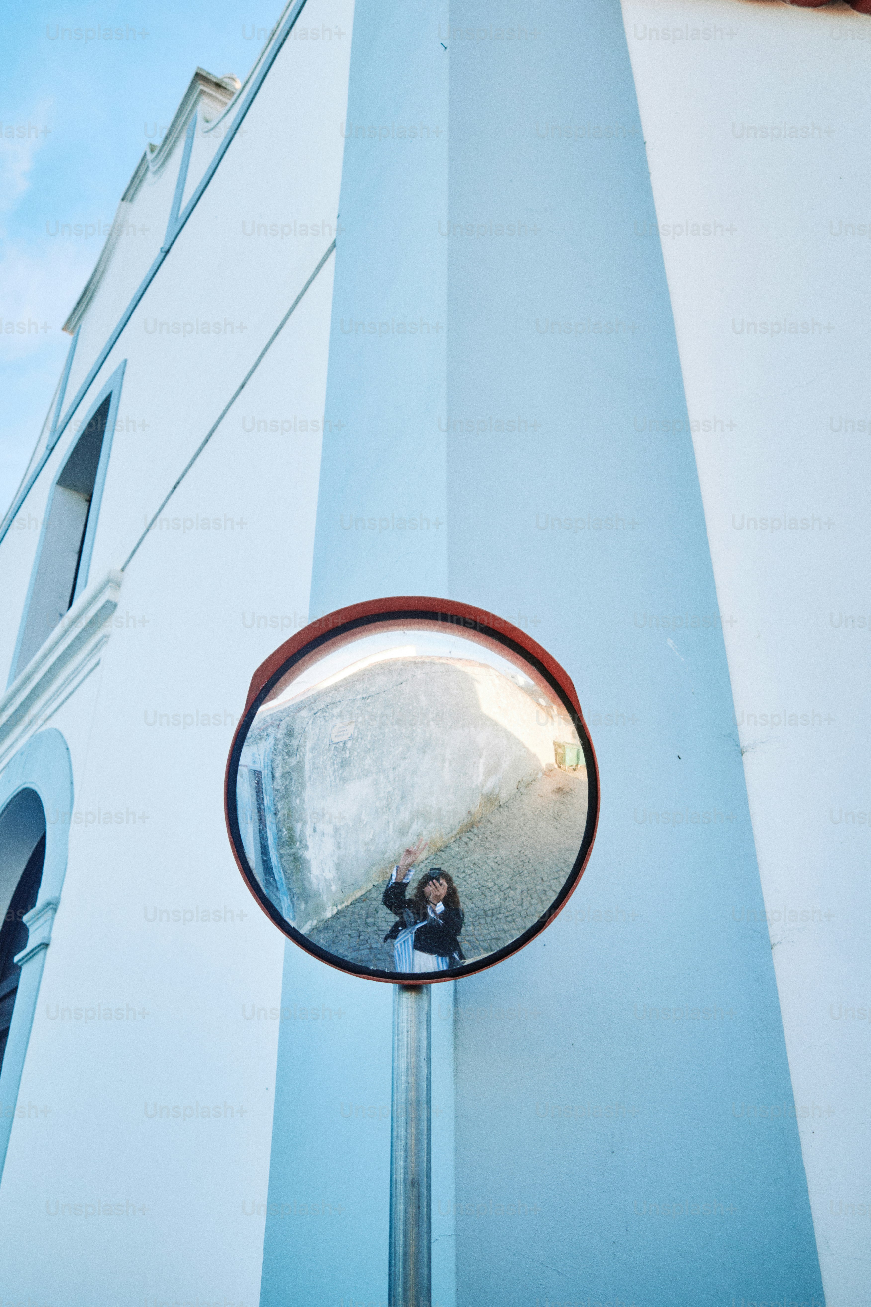 Persona tomándose un selfie en un espejo convexo en un edificio