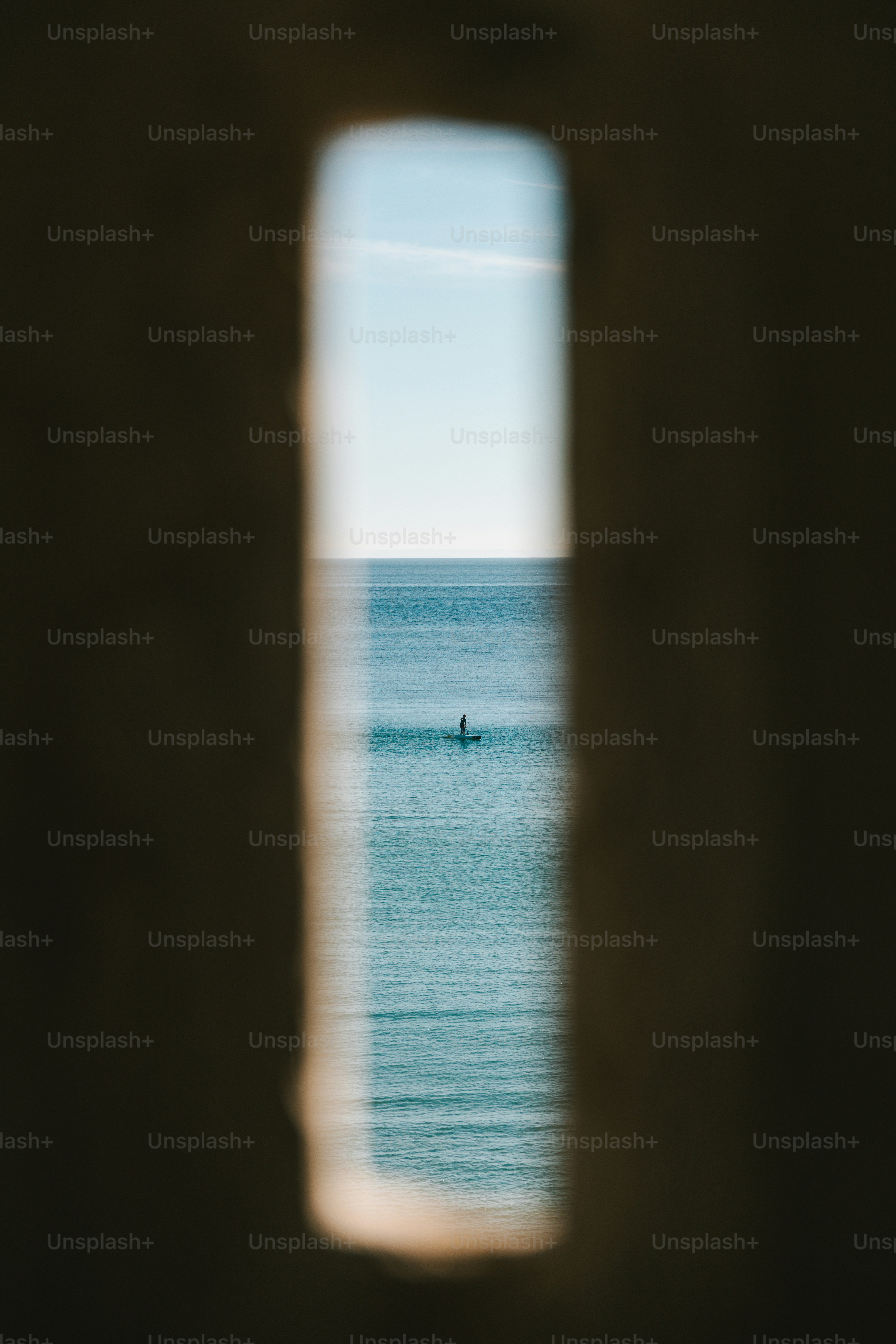 Person paddleboarding on calm blue ocean water.