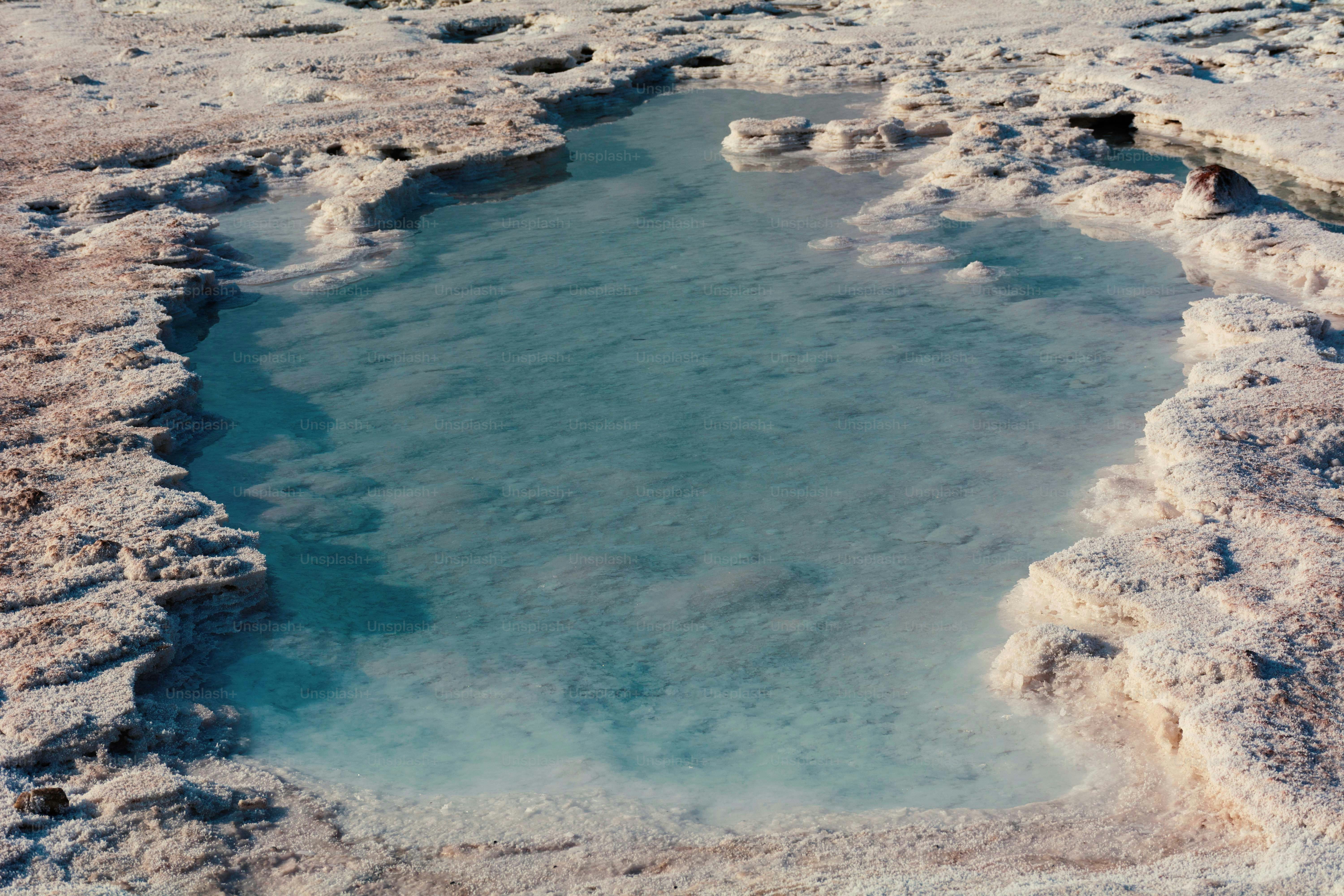 A small pool of turquoise water surrounded by rocky terrain.
