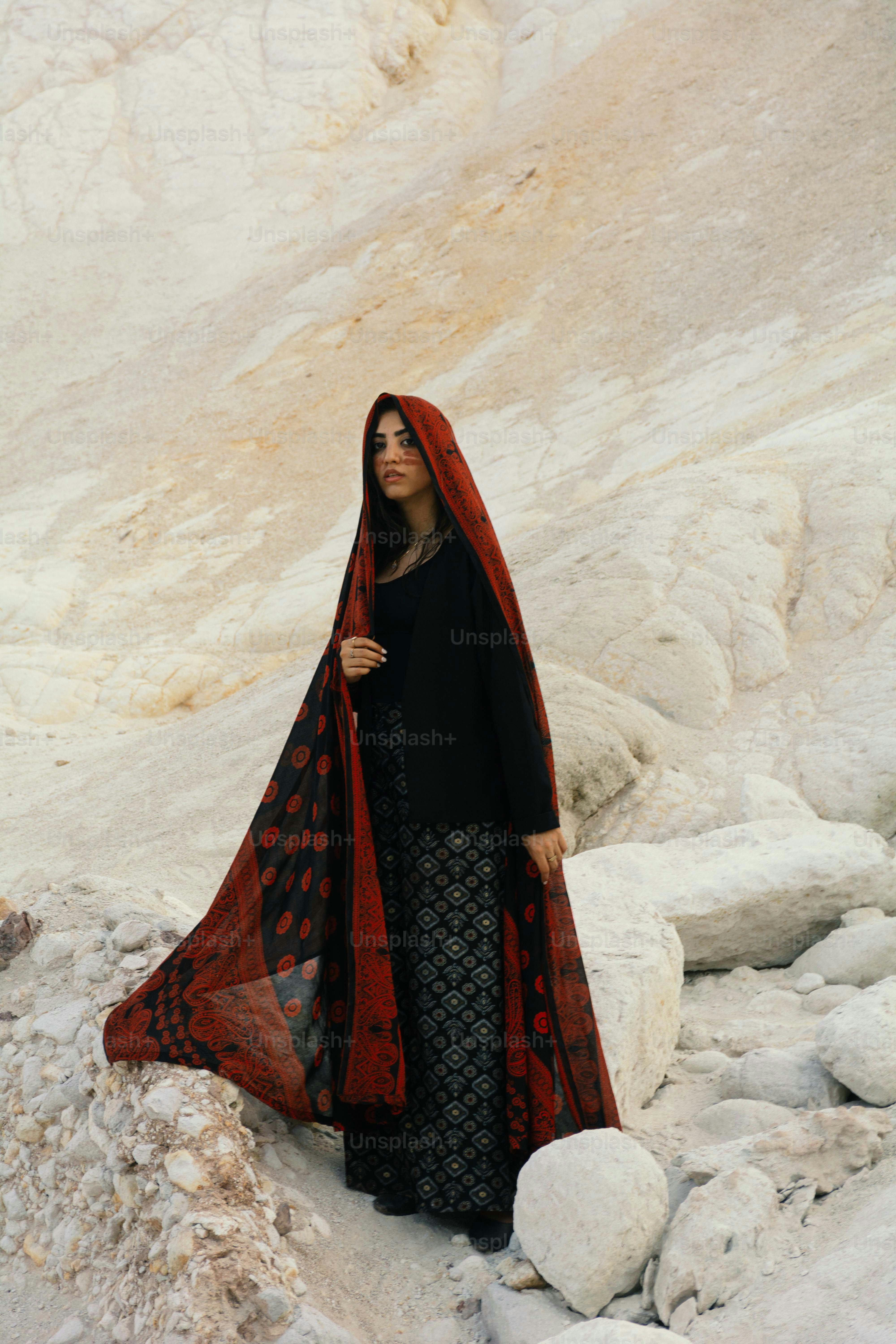 Woman in red and black attire standing amongst rocks