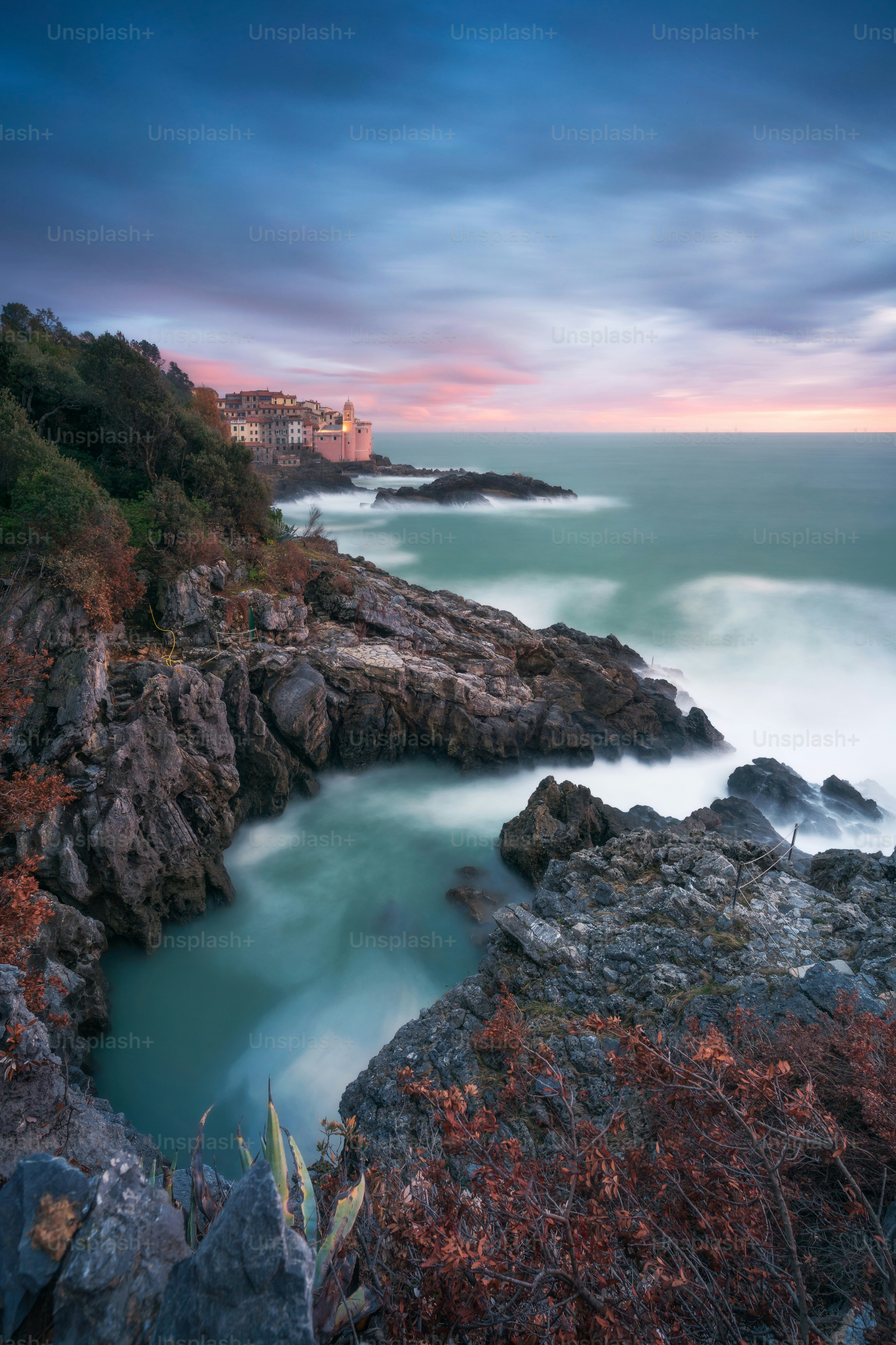 Rocky coastline with crashing waves at sunset.