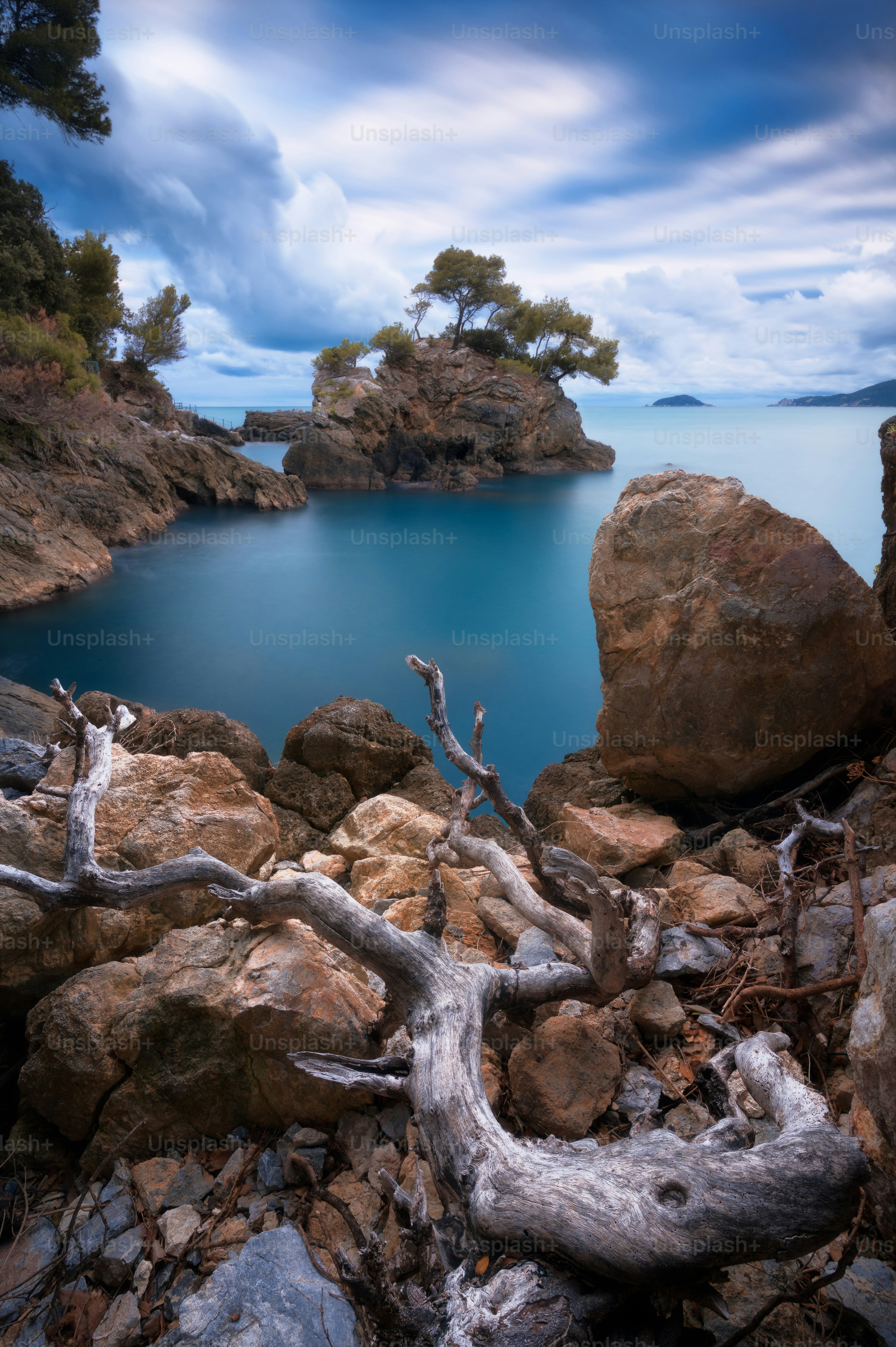 Rocky coastline with a small island and calm blue water.