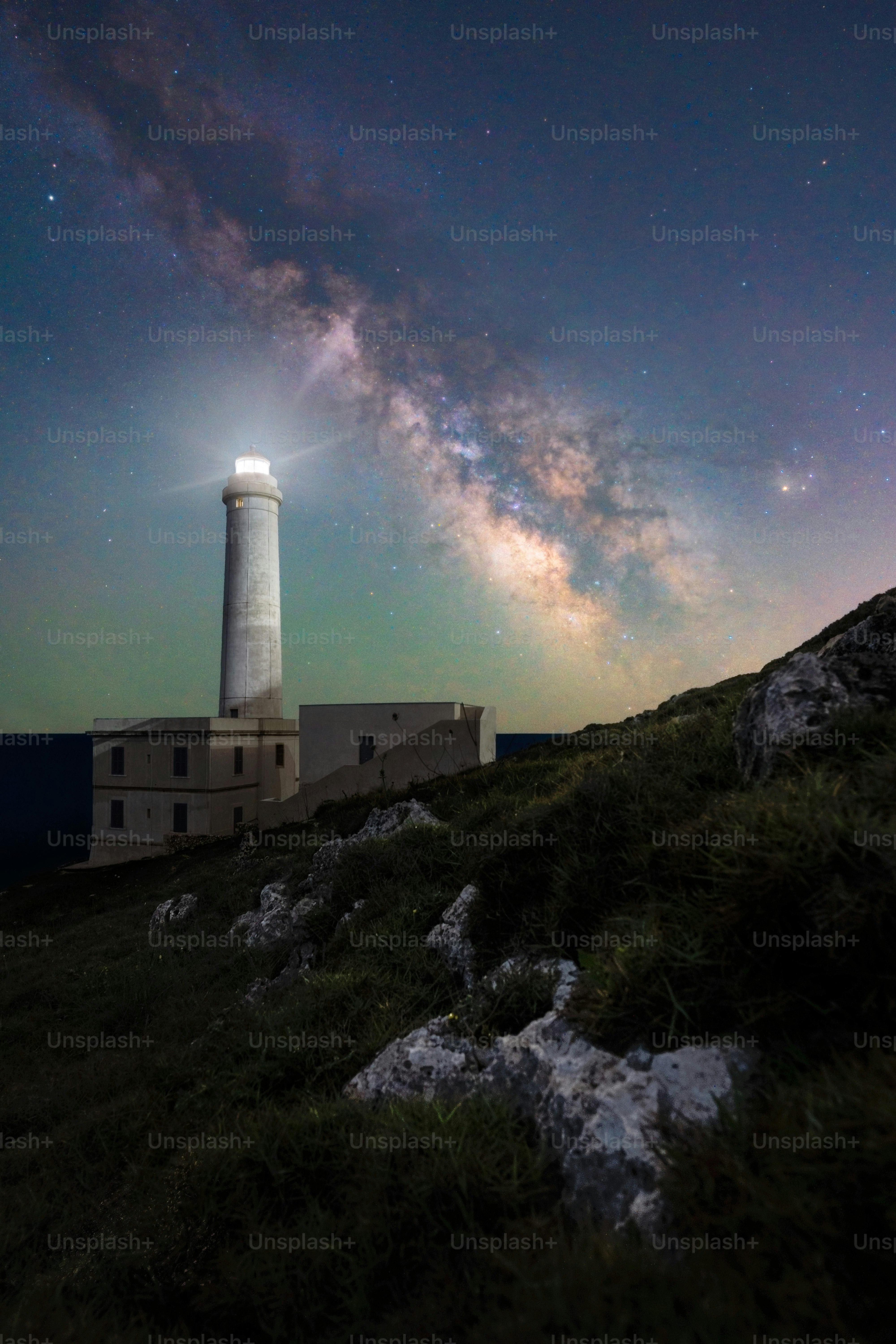 Lighthouse illuminated under the milky way galaxy.