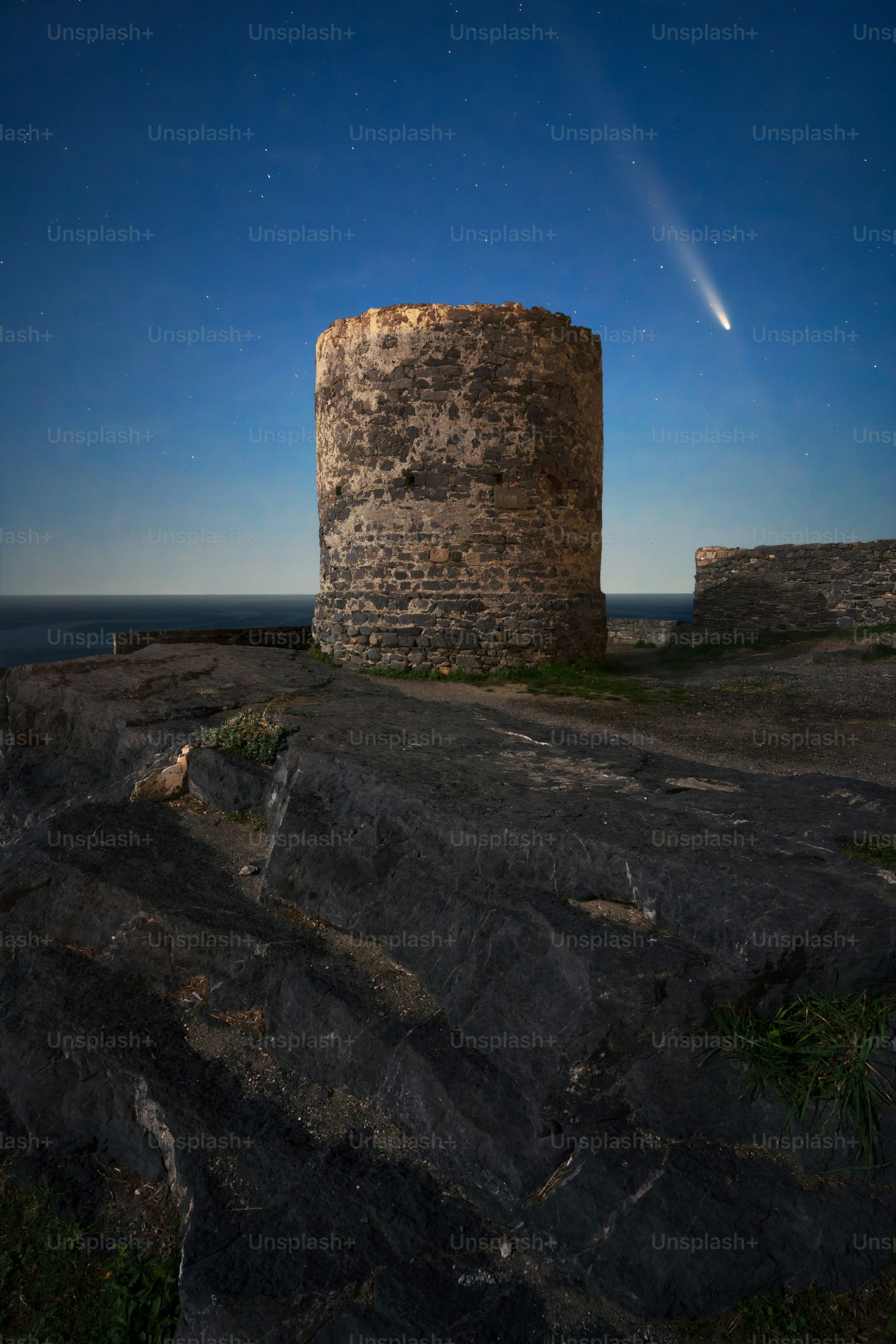 Ancient stone tower under a starry night sky with comet.