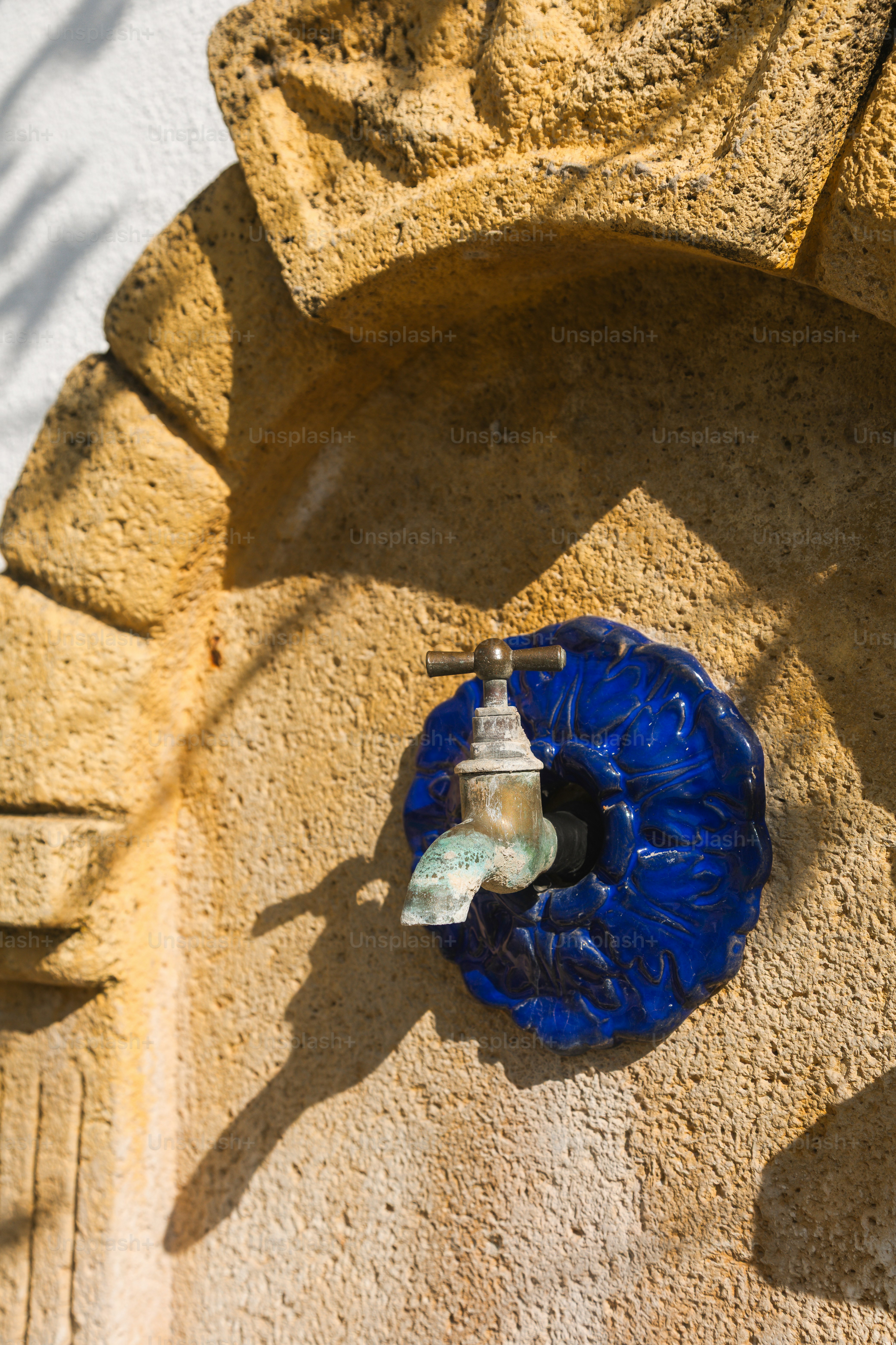 A weathered faucet on a decorative blue tile.