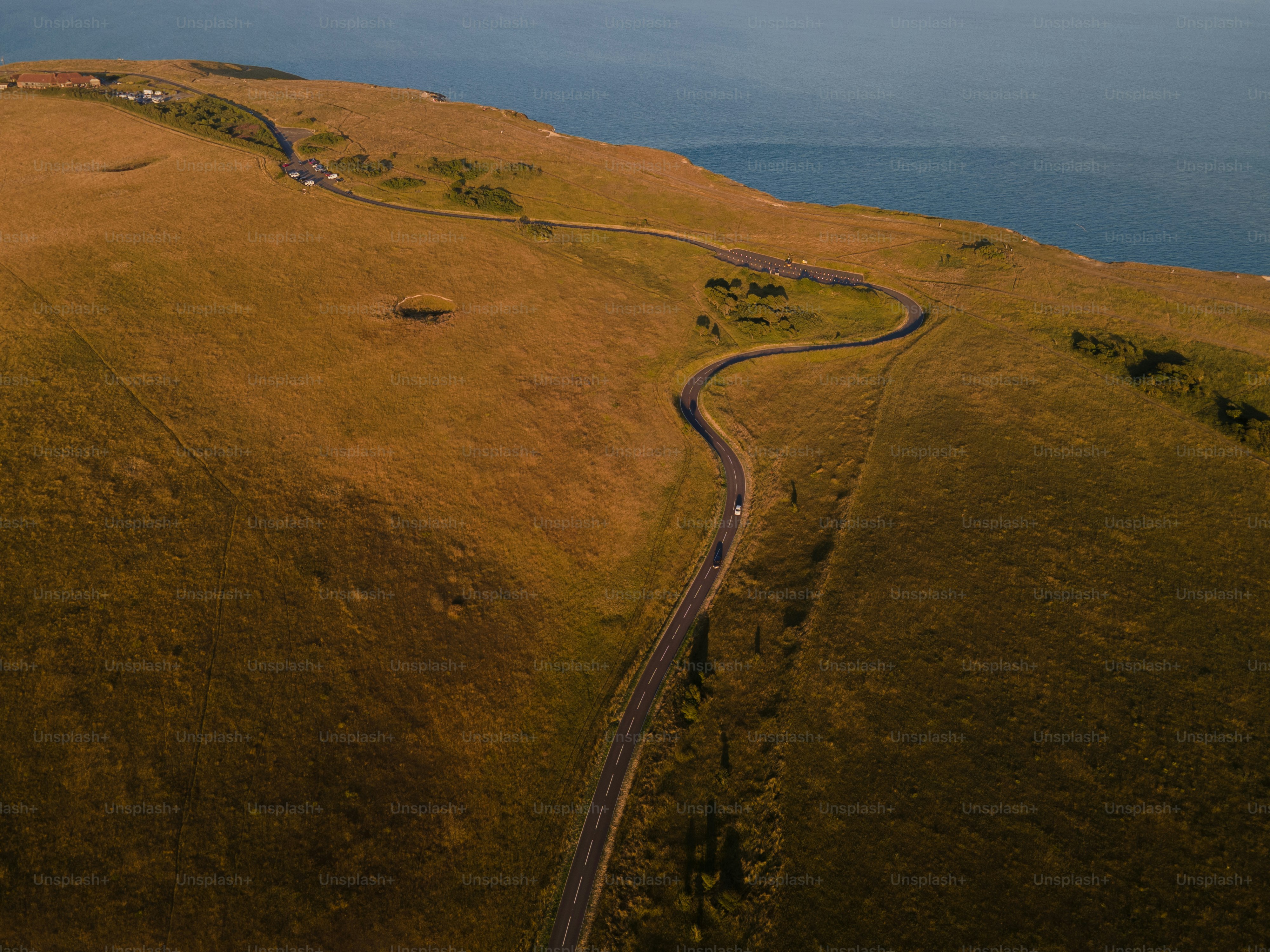 Winding road through a grassy hillside towards the ocean