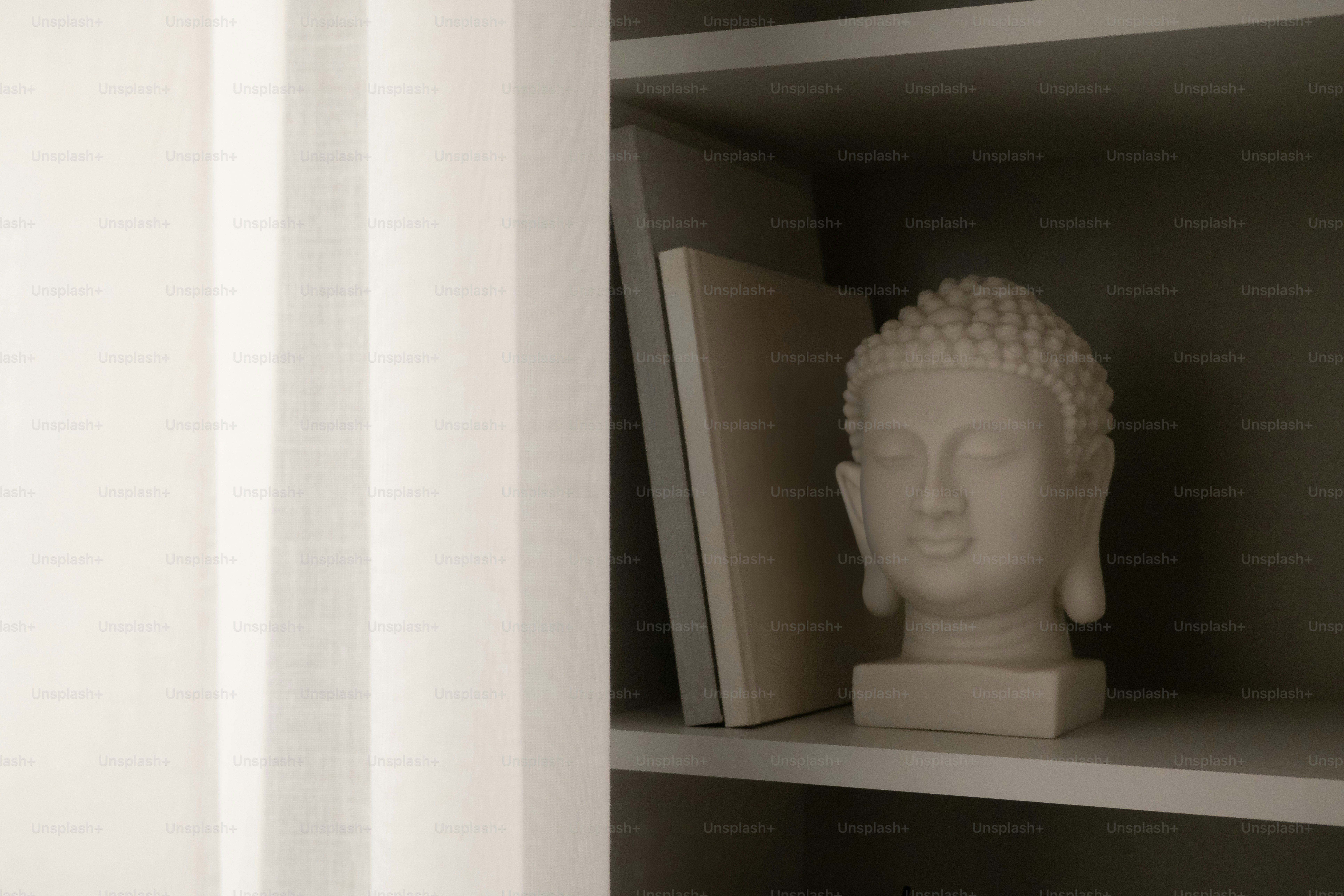 White buddha head statue on a shelf.