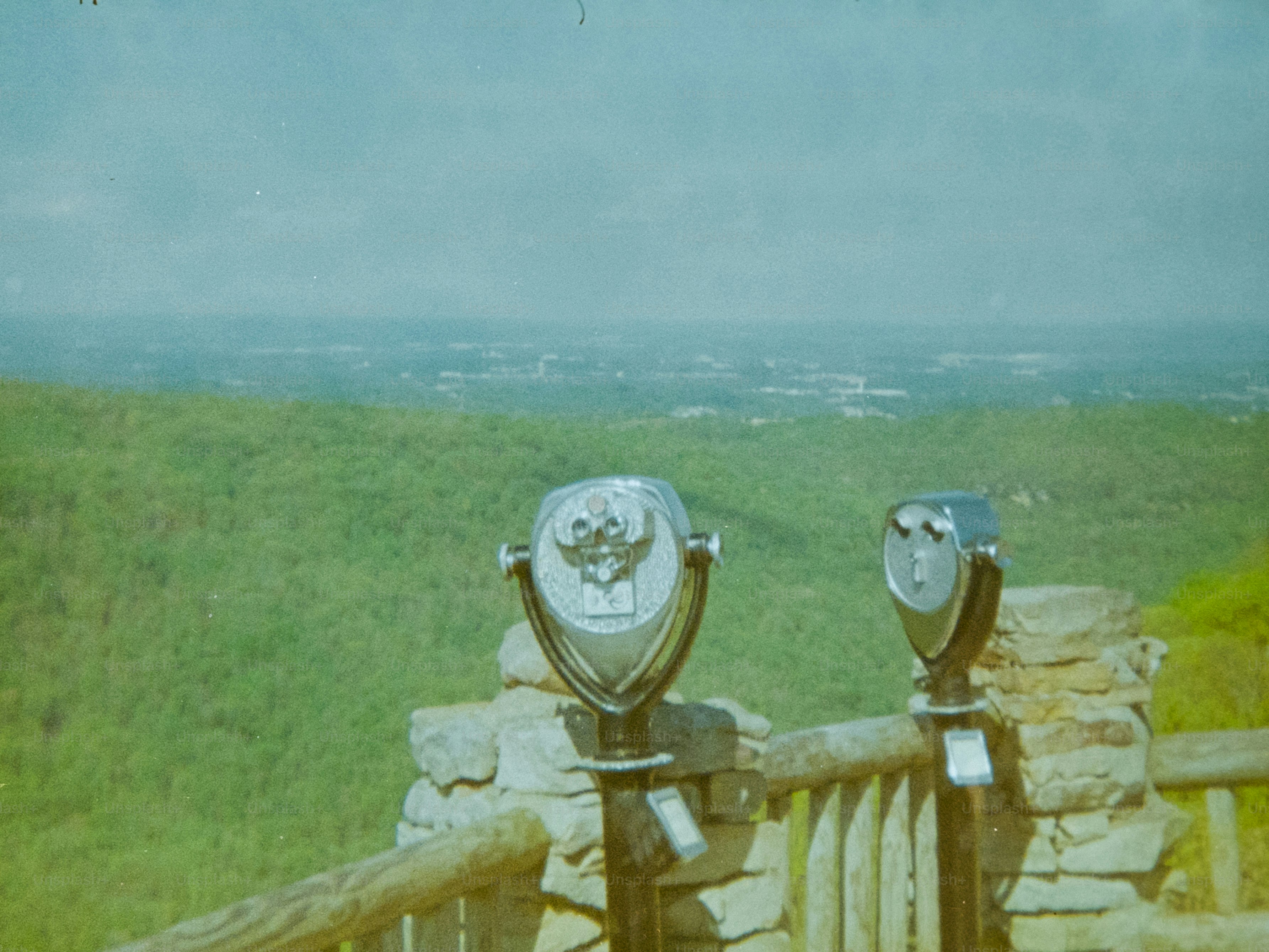 Deux jumelles surplombent un paysage verdoyant avec une ville lointaine.