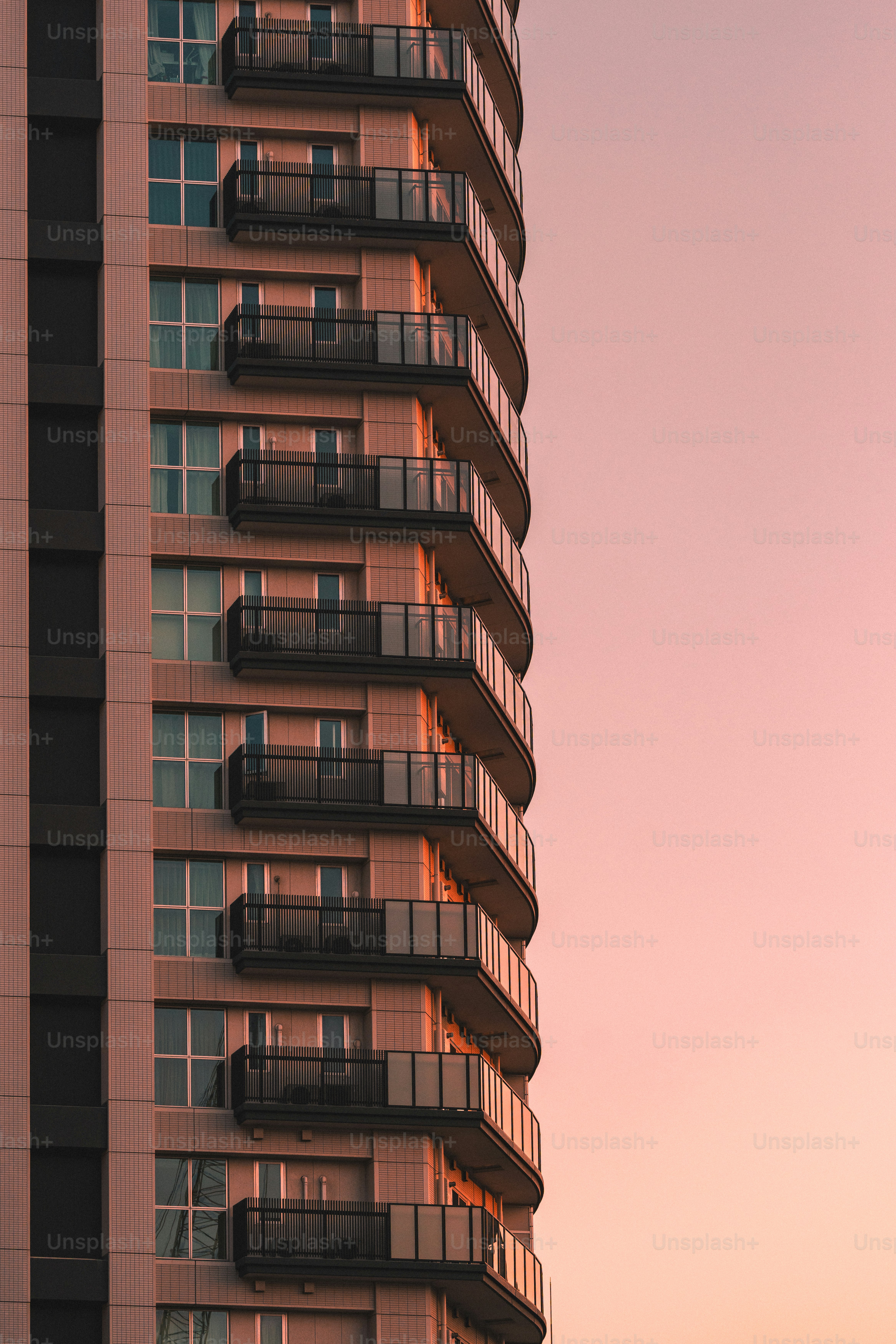 Modern apartment building with balconies at sunset.