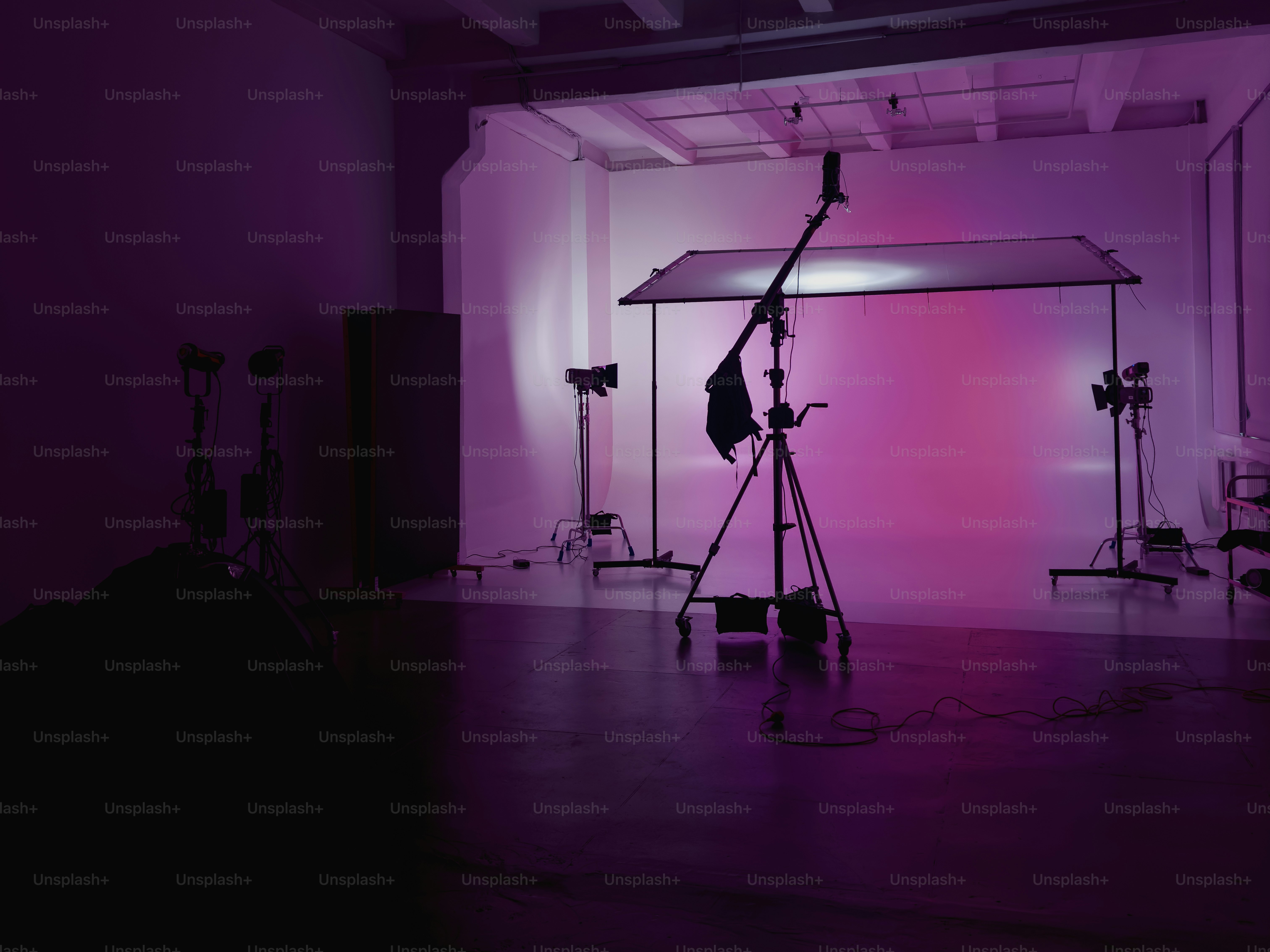 A photography studio with pink lighting and equipment.