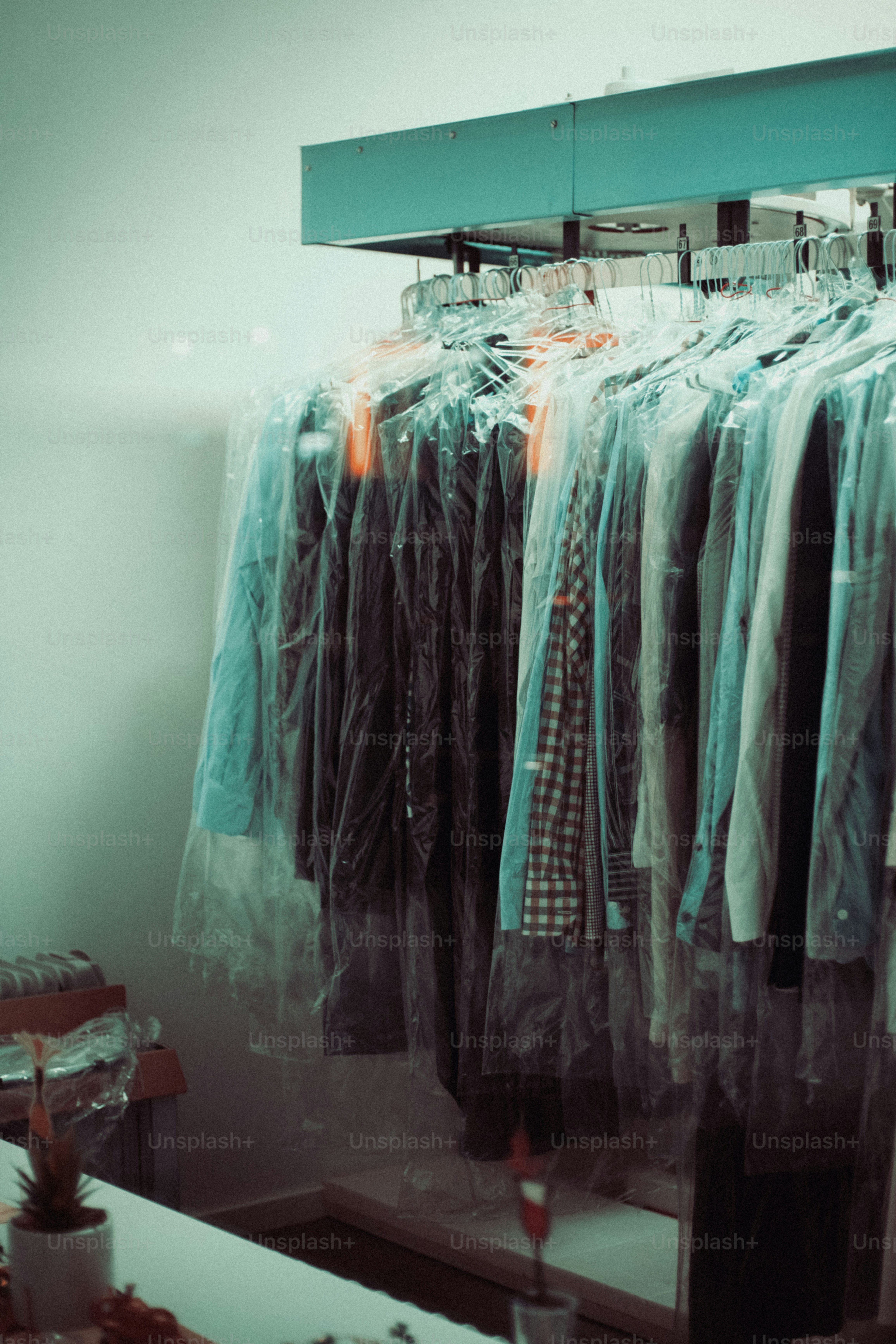 Kleidung hängt in Plastik-Reinigungstüten.