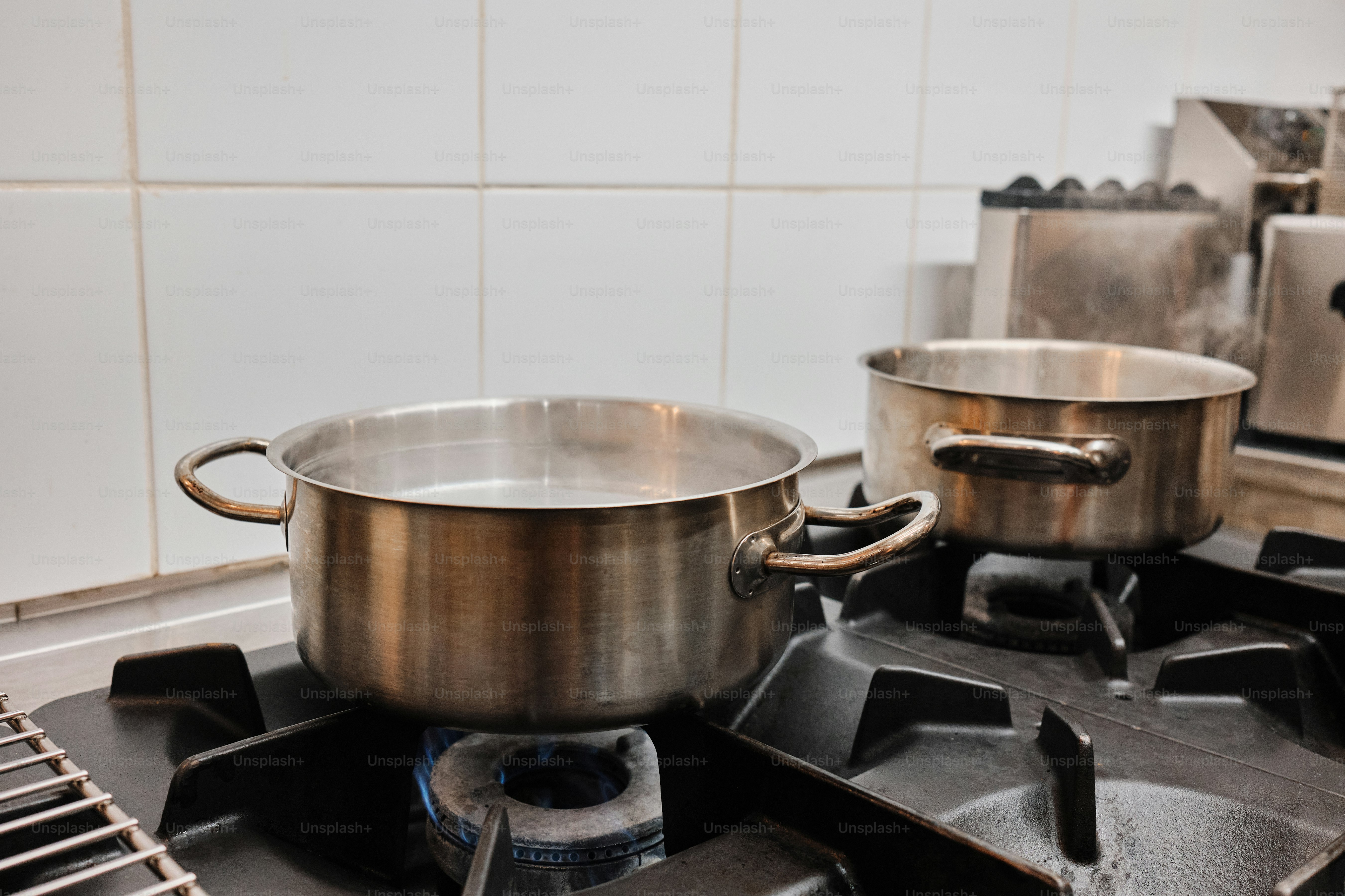 Two pots boiling water on a gas stove.