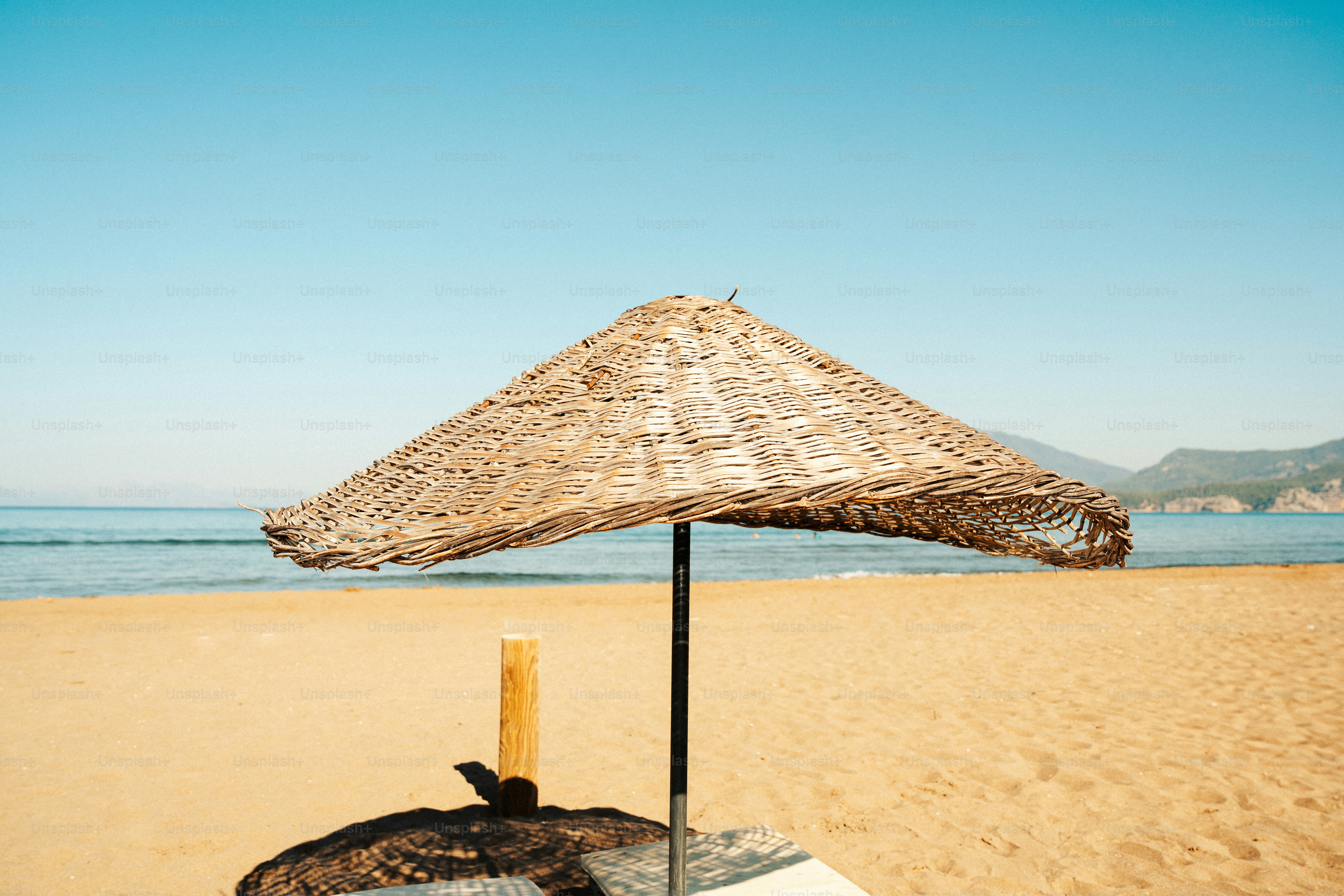 A straw umbrella on a sandy beach with ocean background