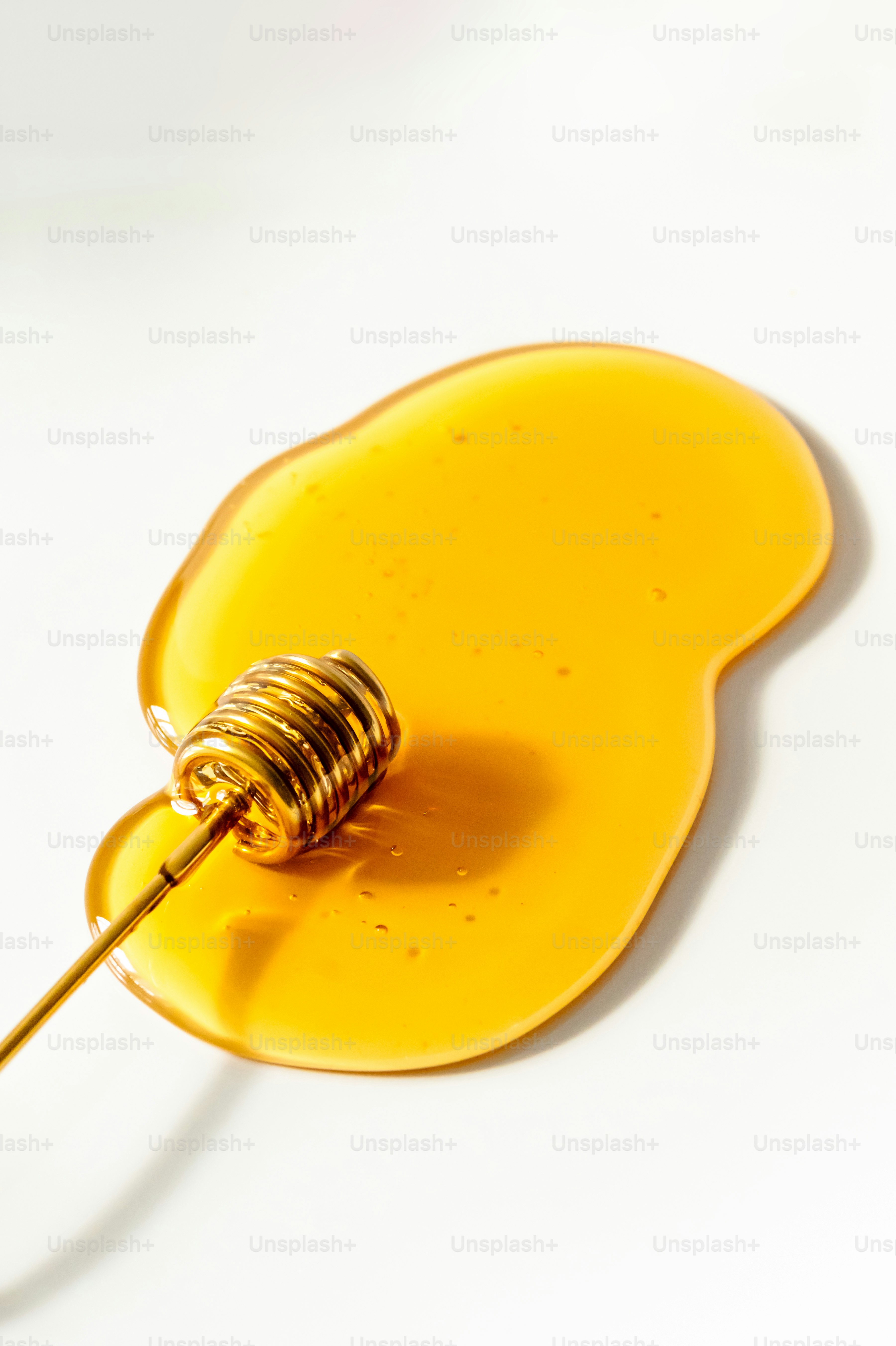 A golden honey dipper rests in a pool of honey.