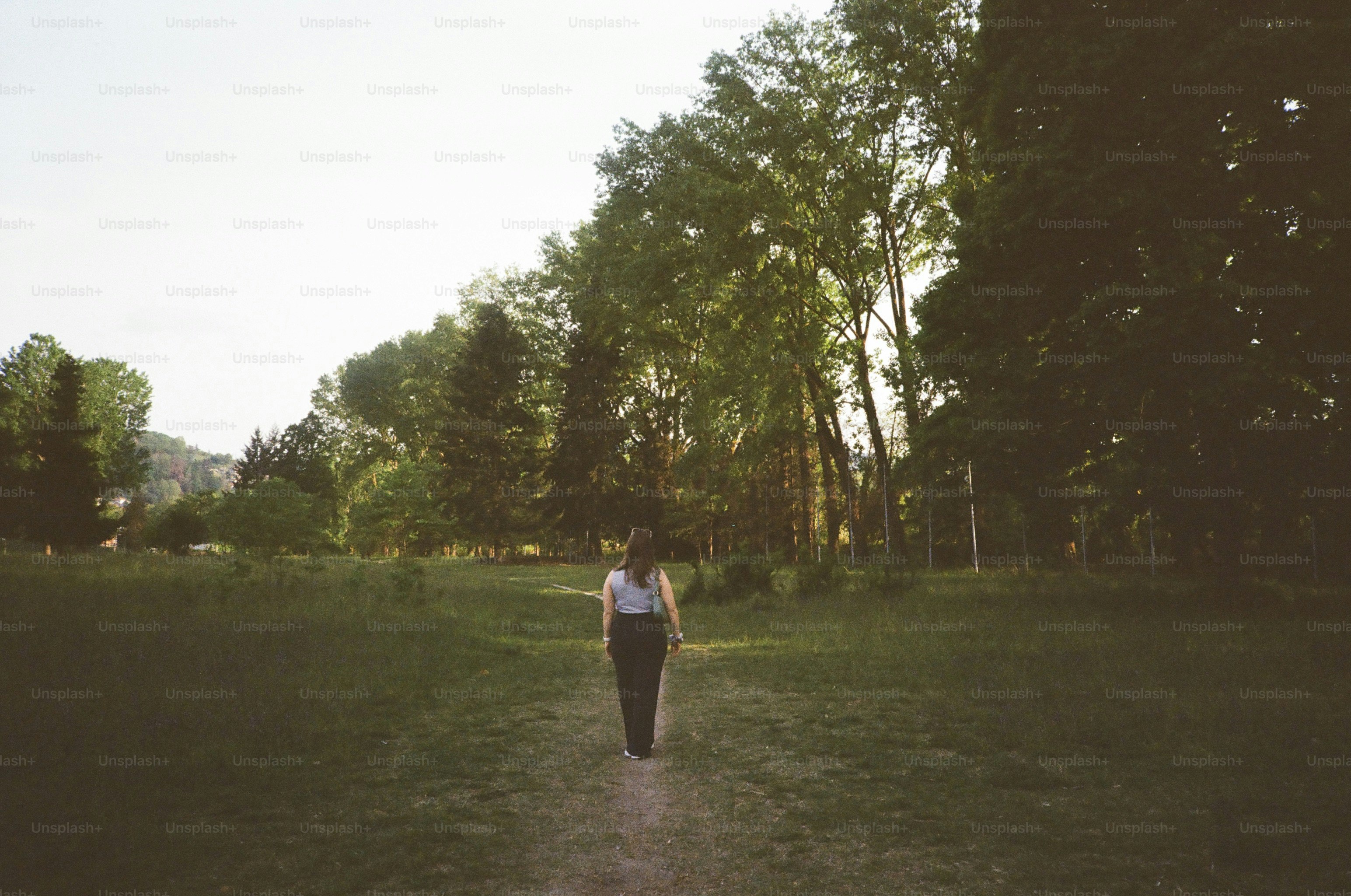 Mujer caminando por un sendero a través de un campo cubierto de hierba.