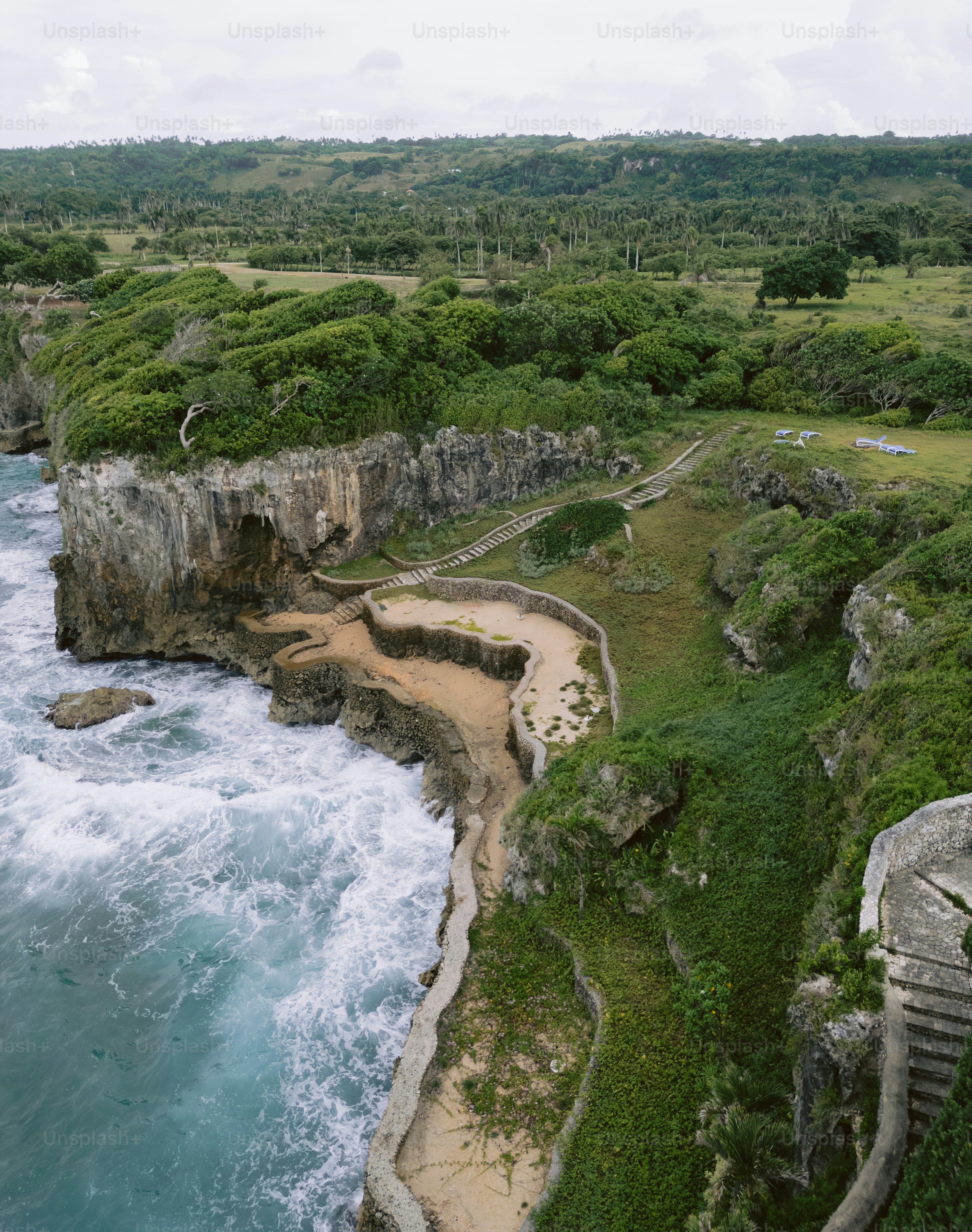 Coastal cliffs with walking path and lush green vegetation.