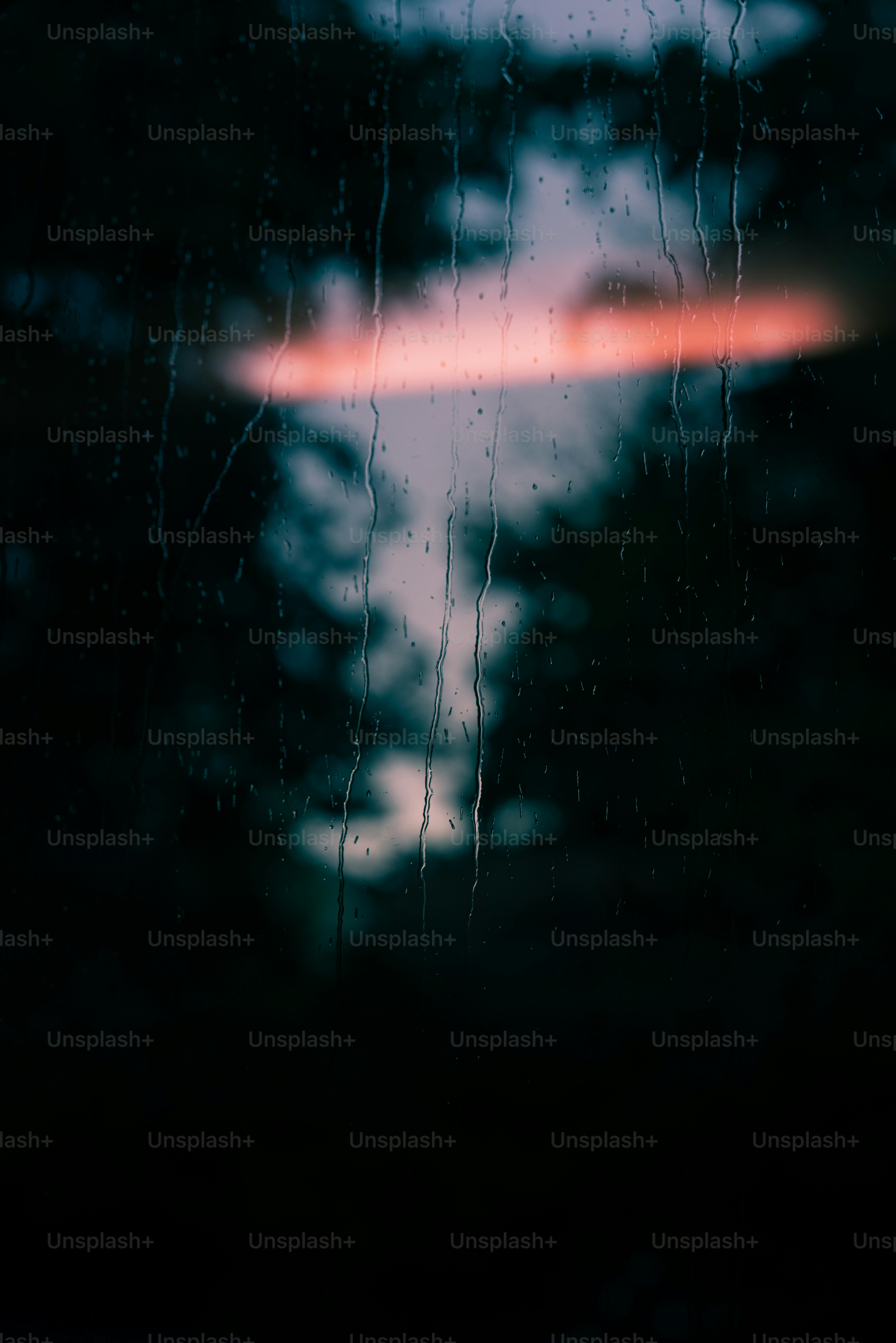 Gocce di pioggia sulla finestra con il cielo al tramonto dietro.