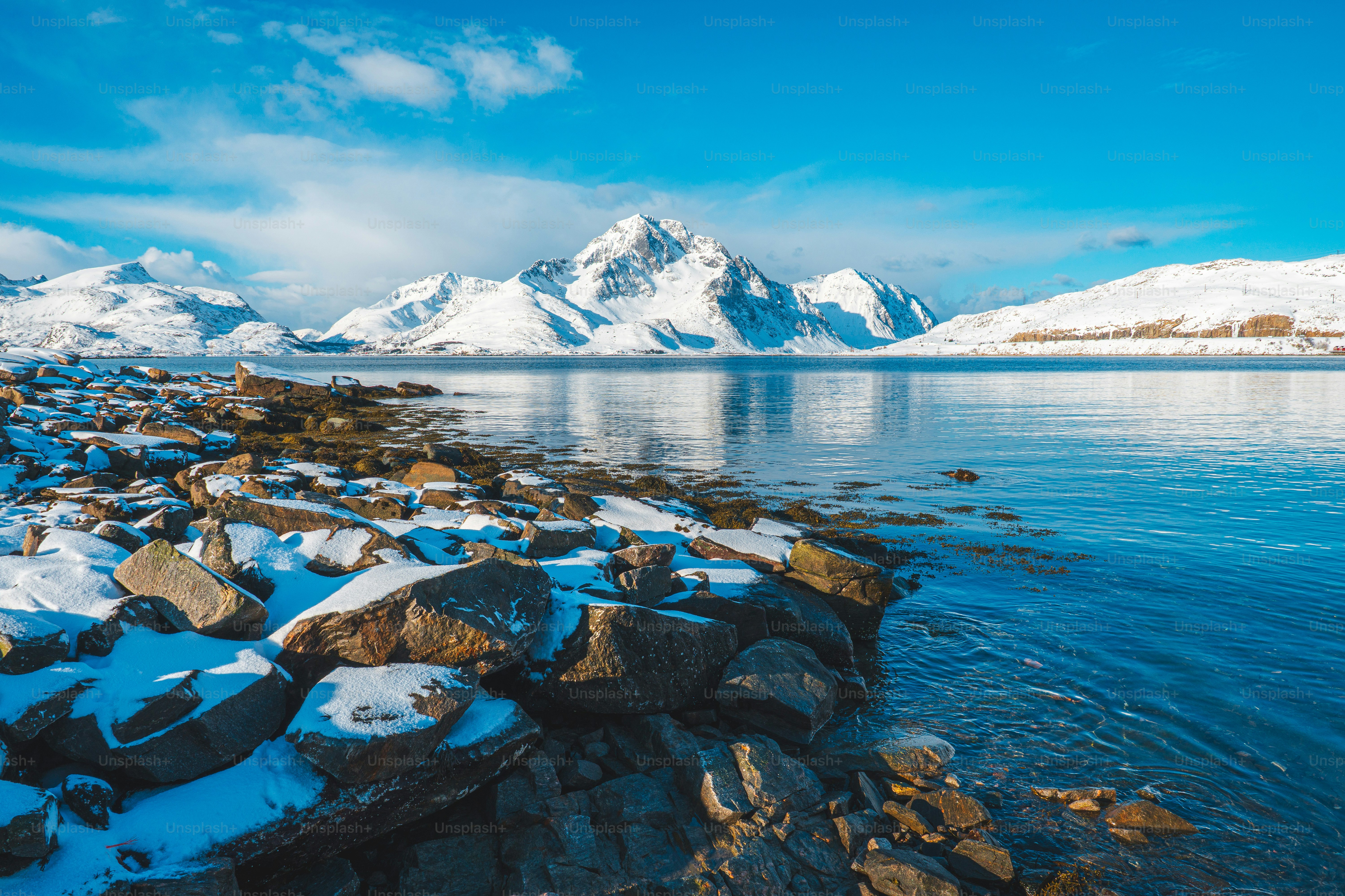 Snowy mountains reflected in calm blue water