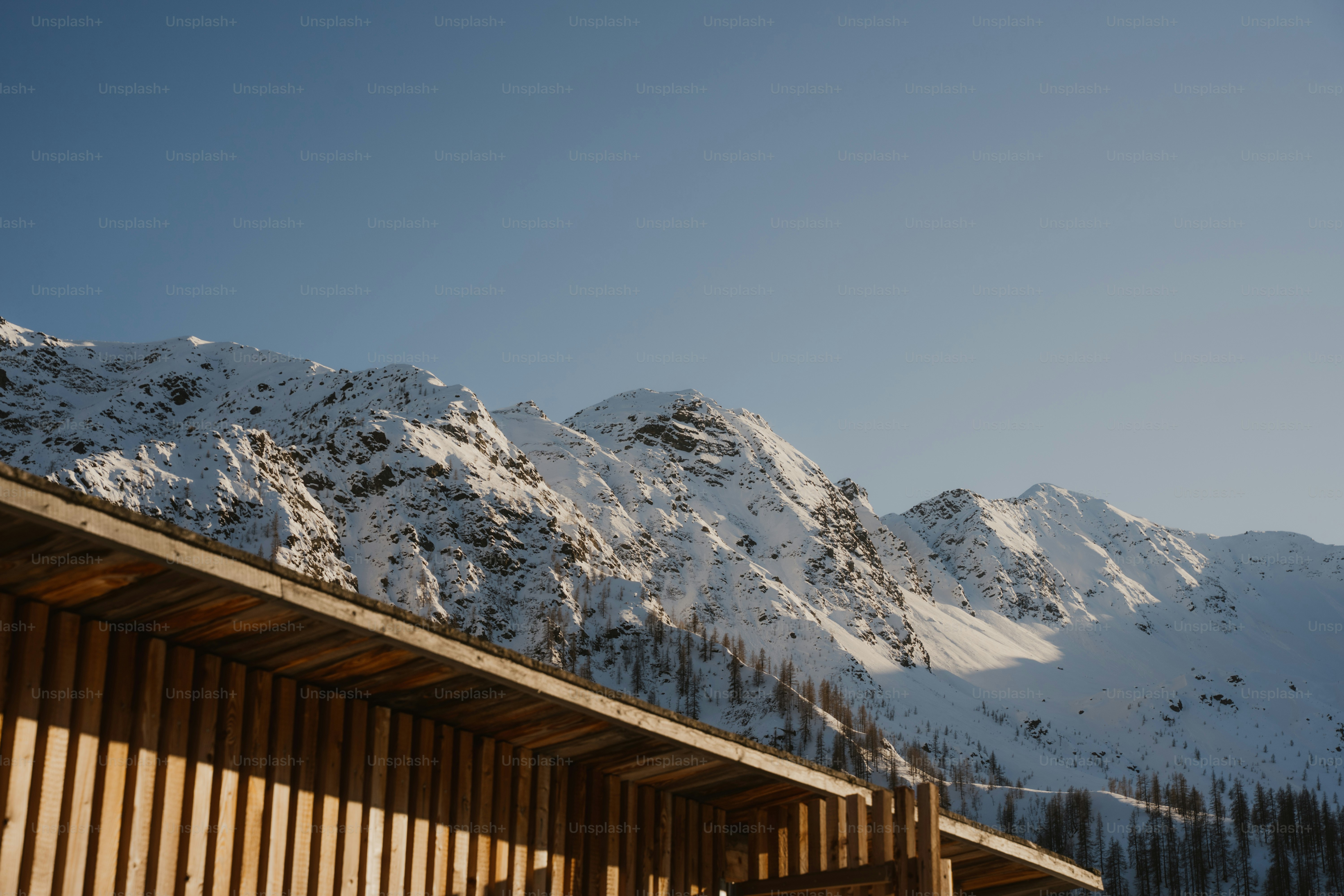 Wooden cabin roof with snow-covered mountains behind