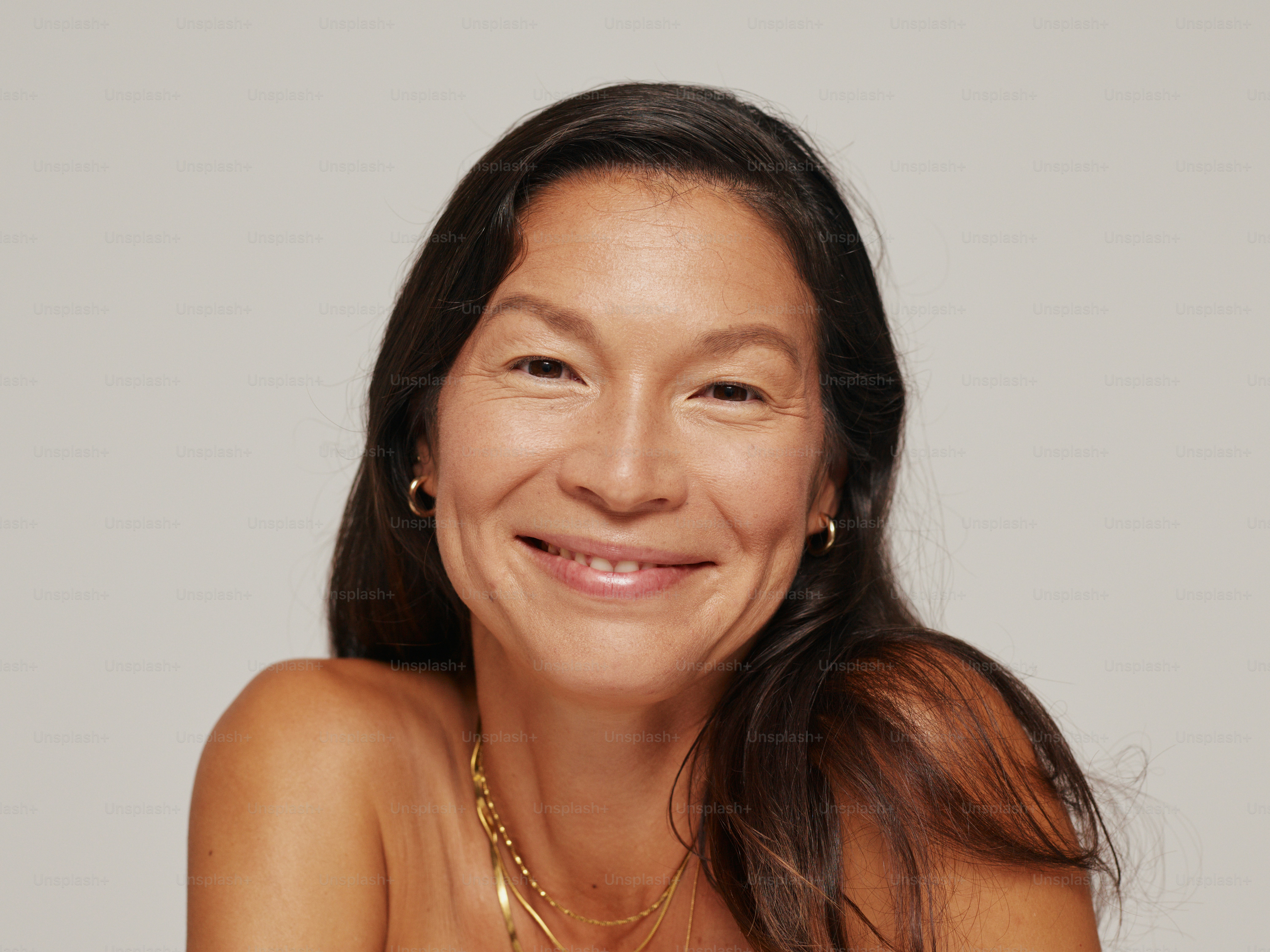 A smiling woman with long dark hair and subtle makeup. photo – Portrait ...