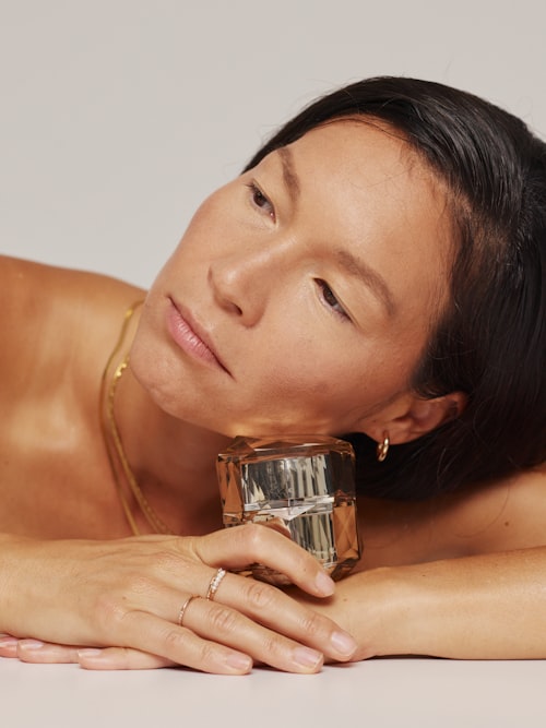 유리 향수병에 기대는 여성 &mdash; 향이 피부에 녹아드는 순간