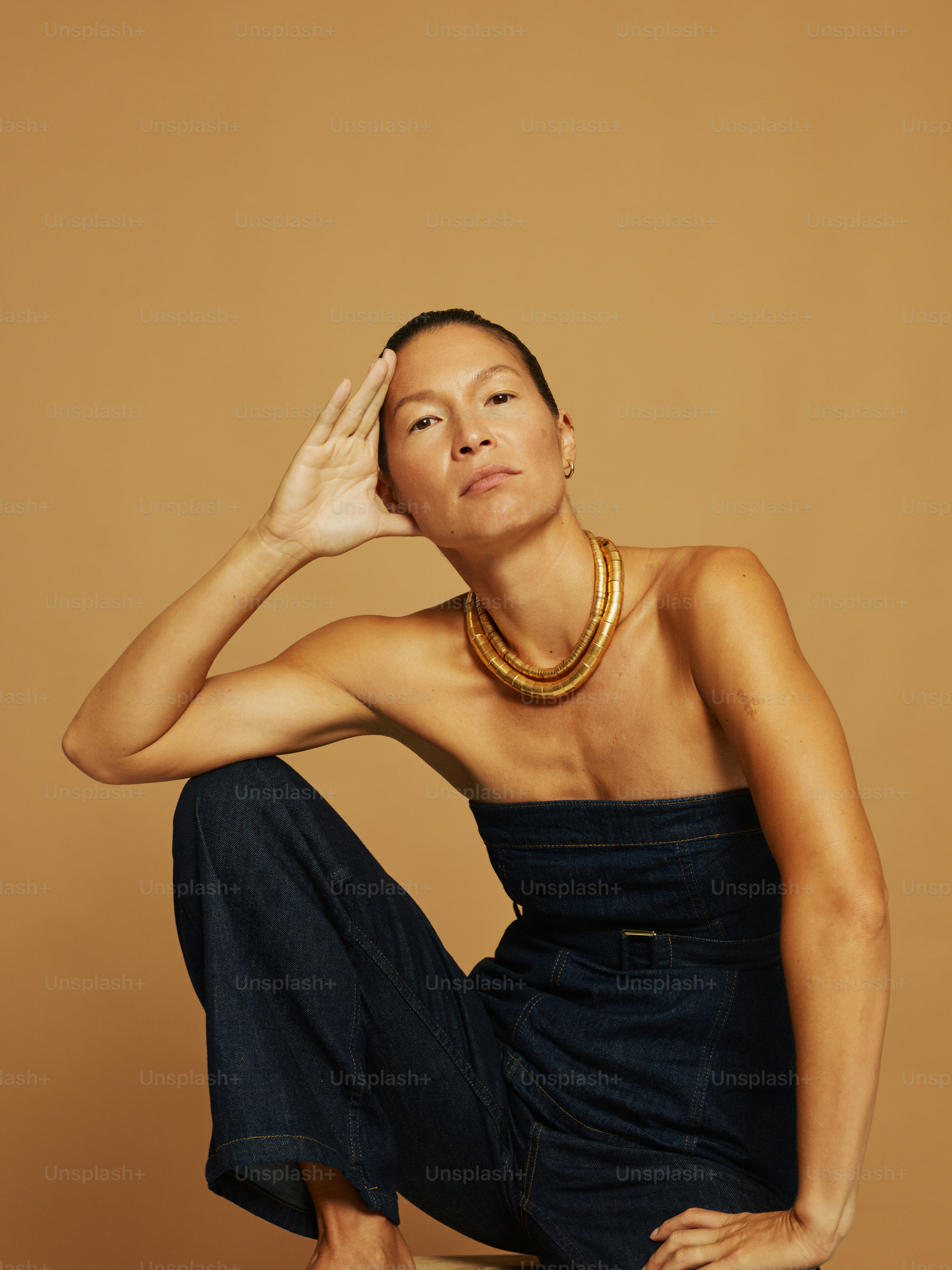 Woman in denim jumpsuit wearing a gold necklace