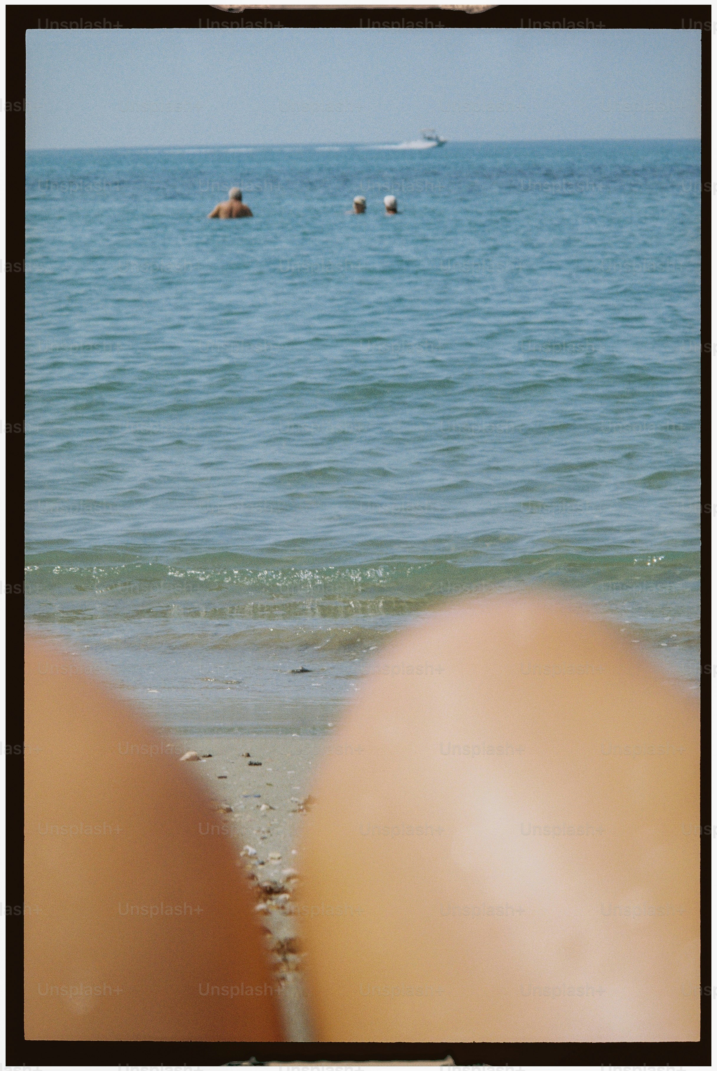People swimming in the ocean with a boat in distance