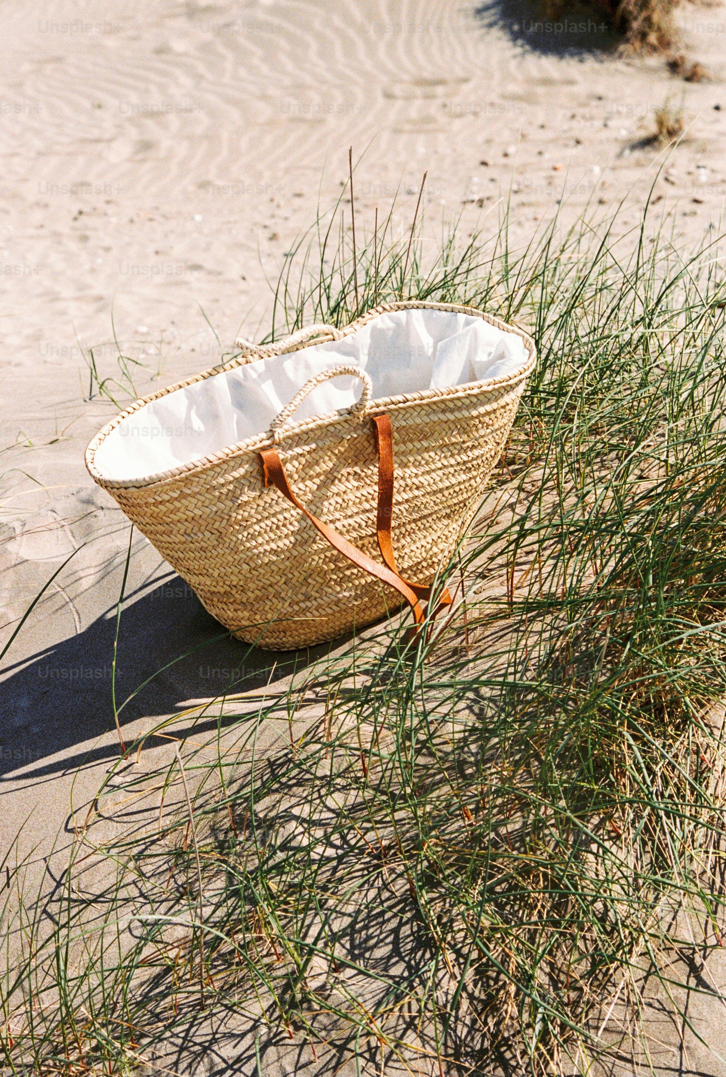 Straw beach bag with leather handles on sand