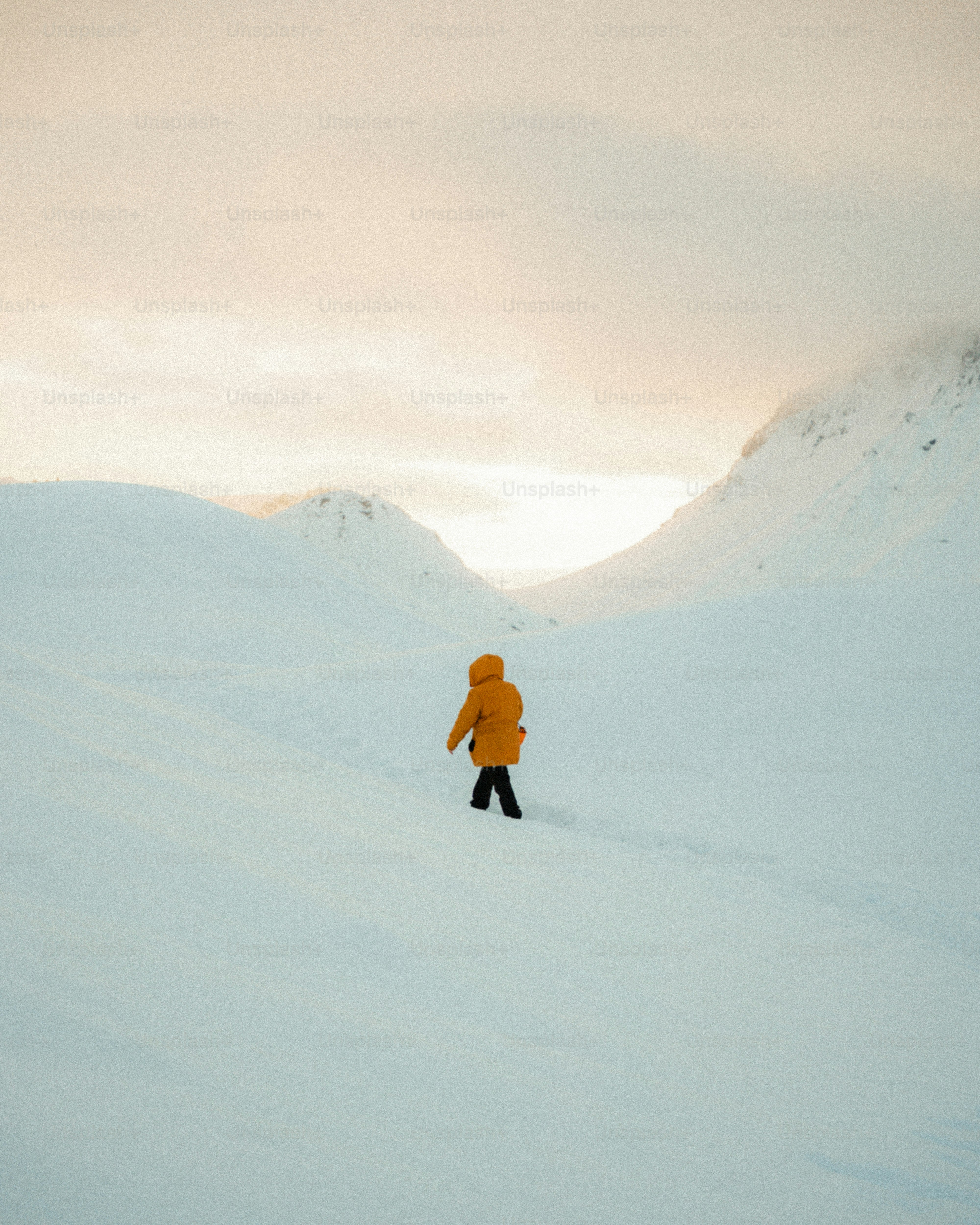 Person in yellow jacket walks through snowy landscape