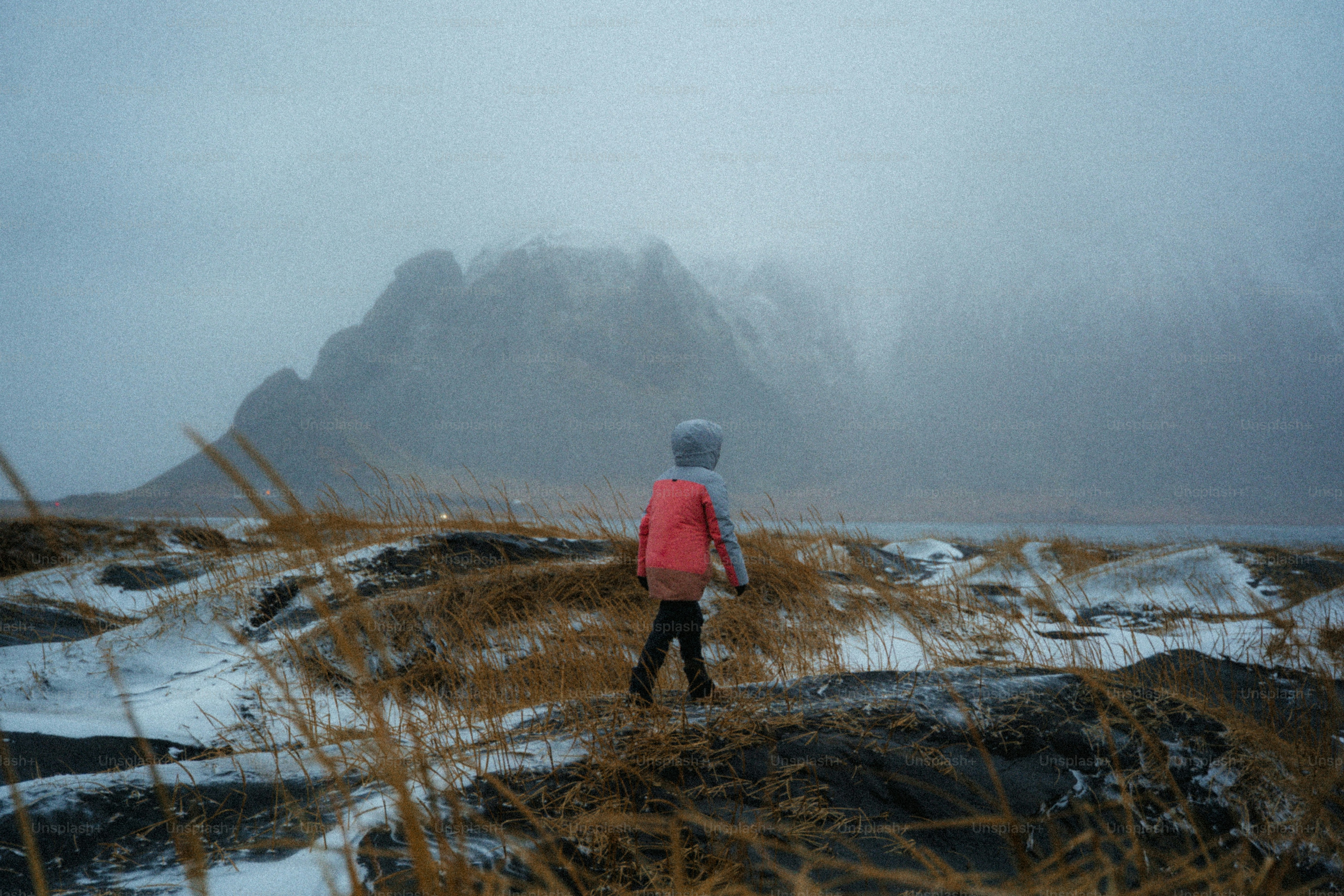 Child walks through snowy landscape towards mountains