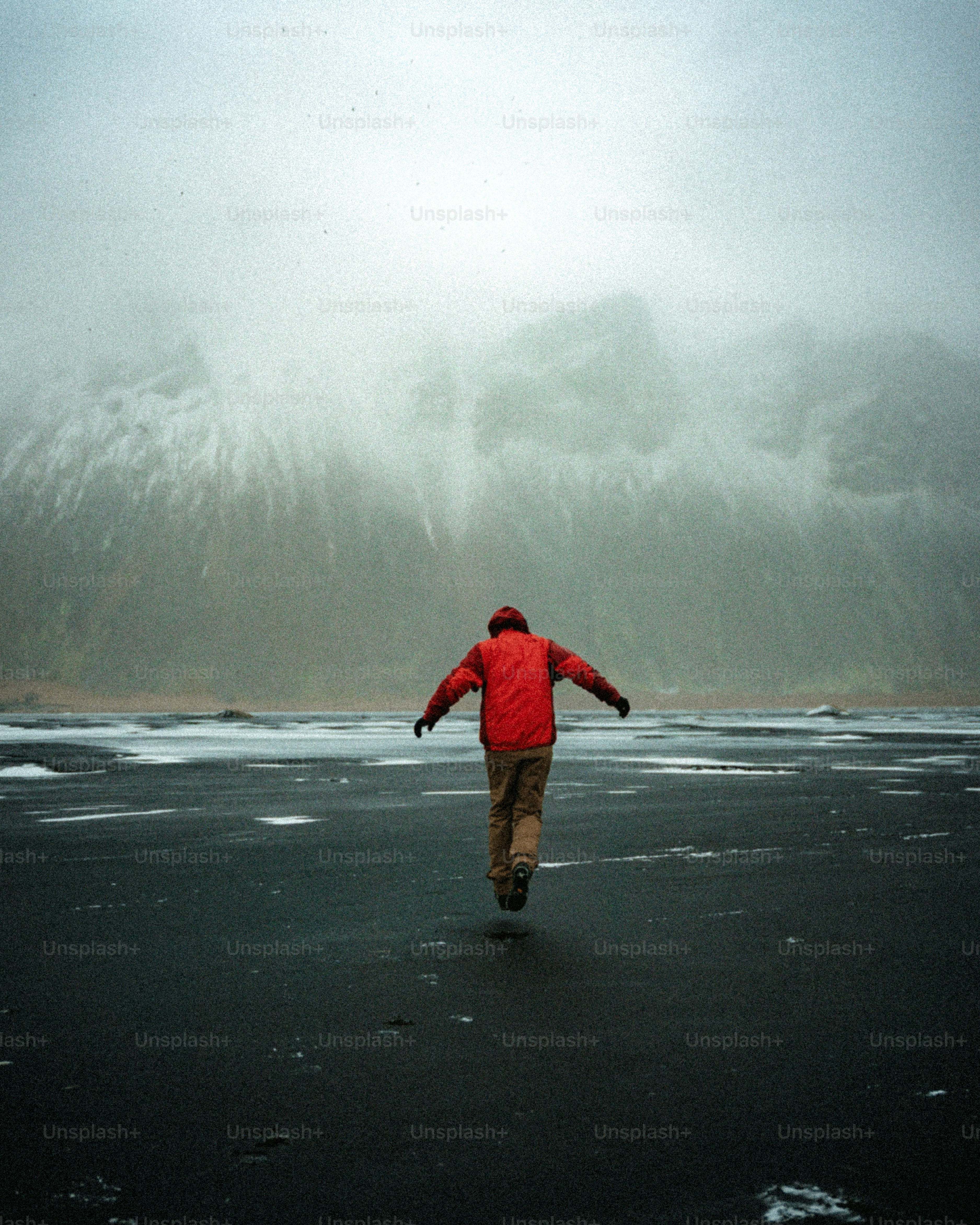 Man in red jacket running on icy landscape