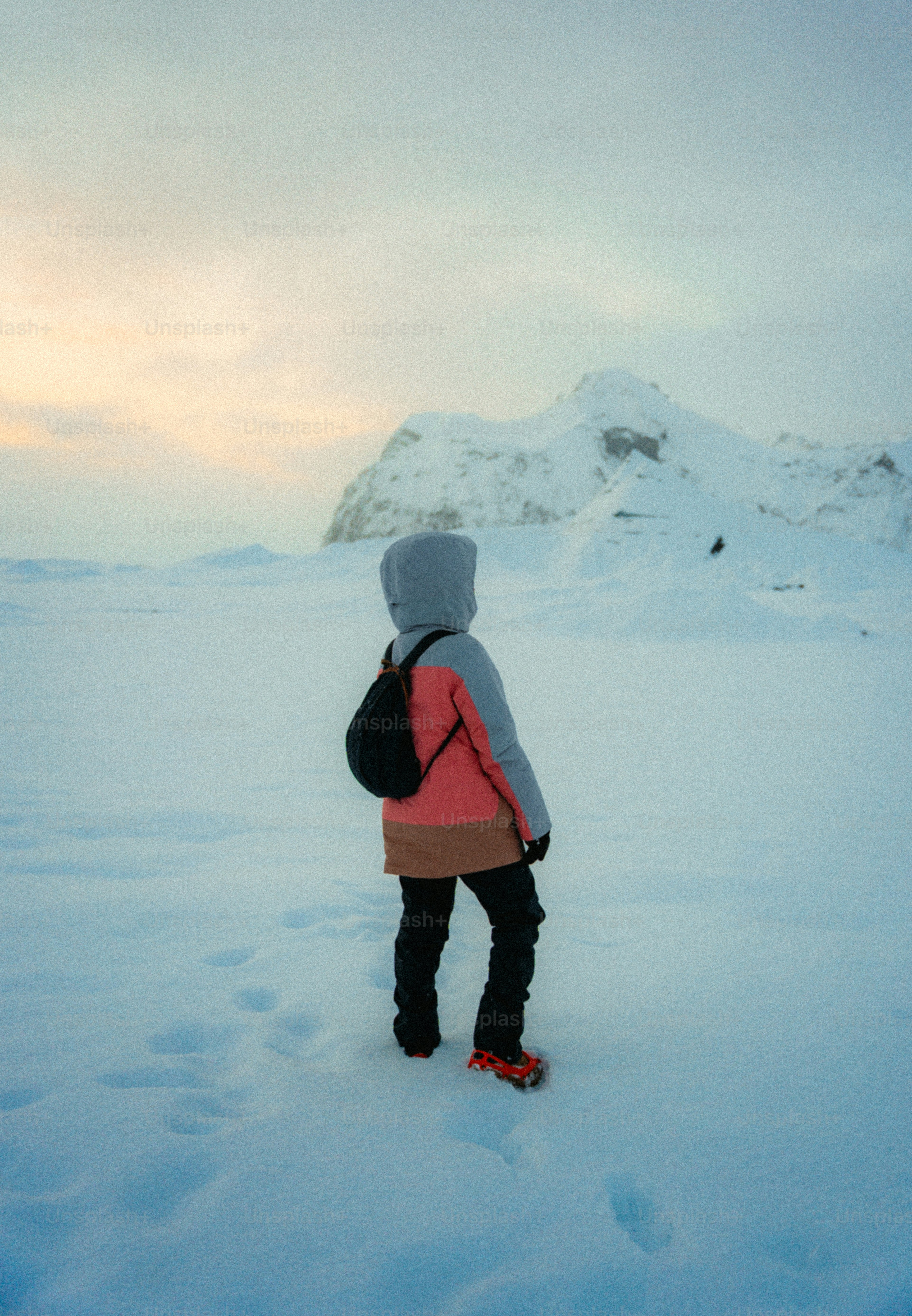 Person in snow gear looking at snowy mountains