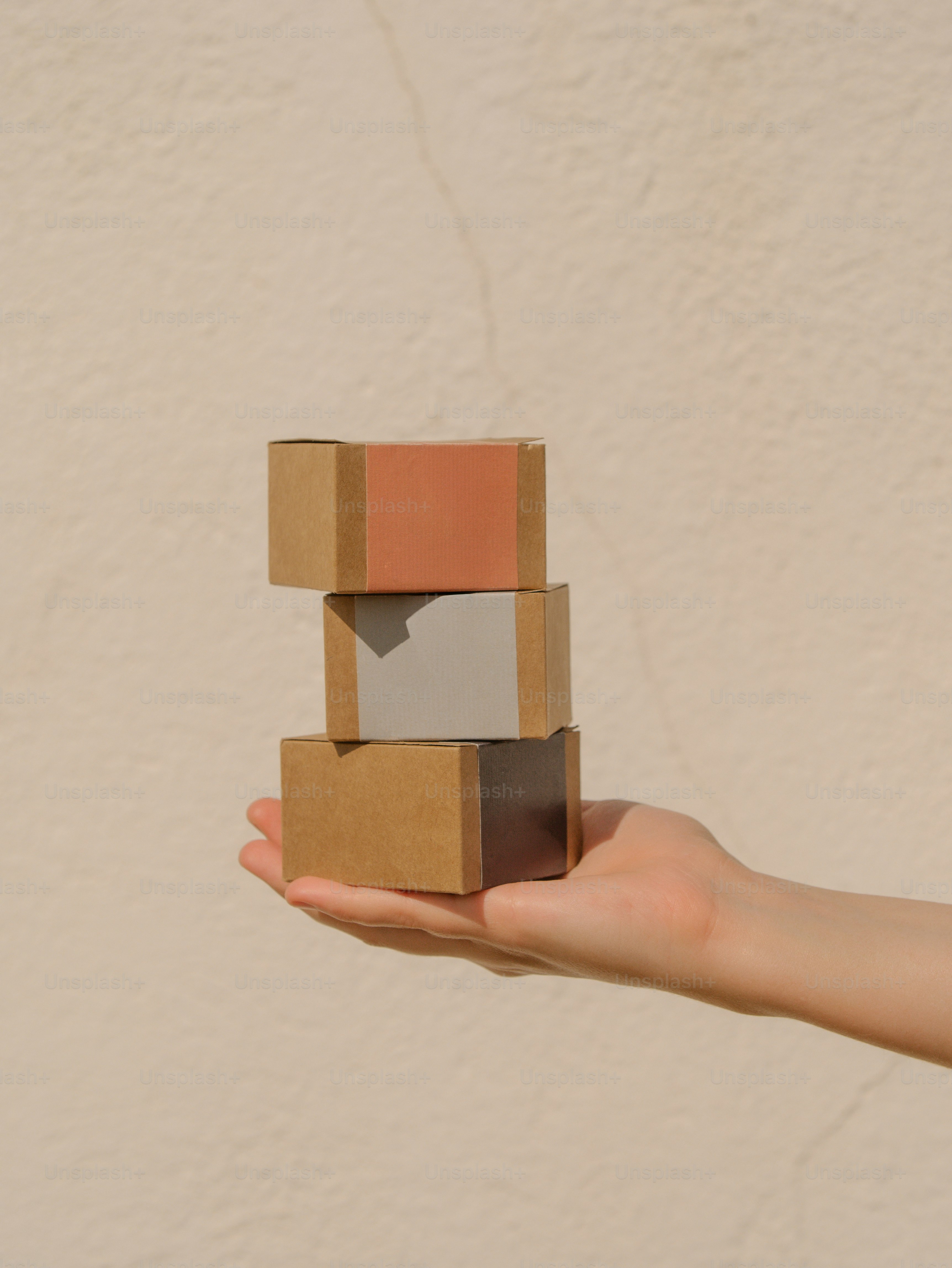 Hand holding three small cardboard boxes stacked photo – Image on Unsplash