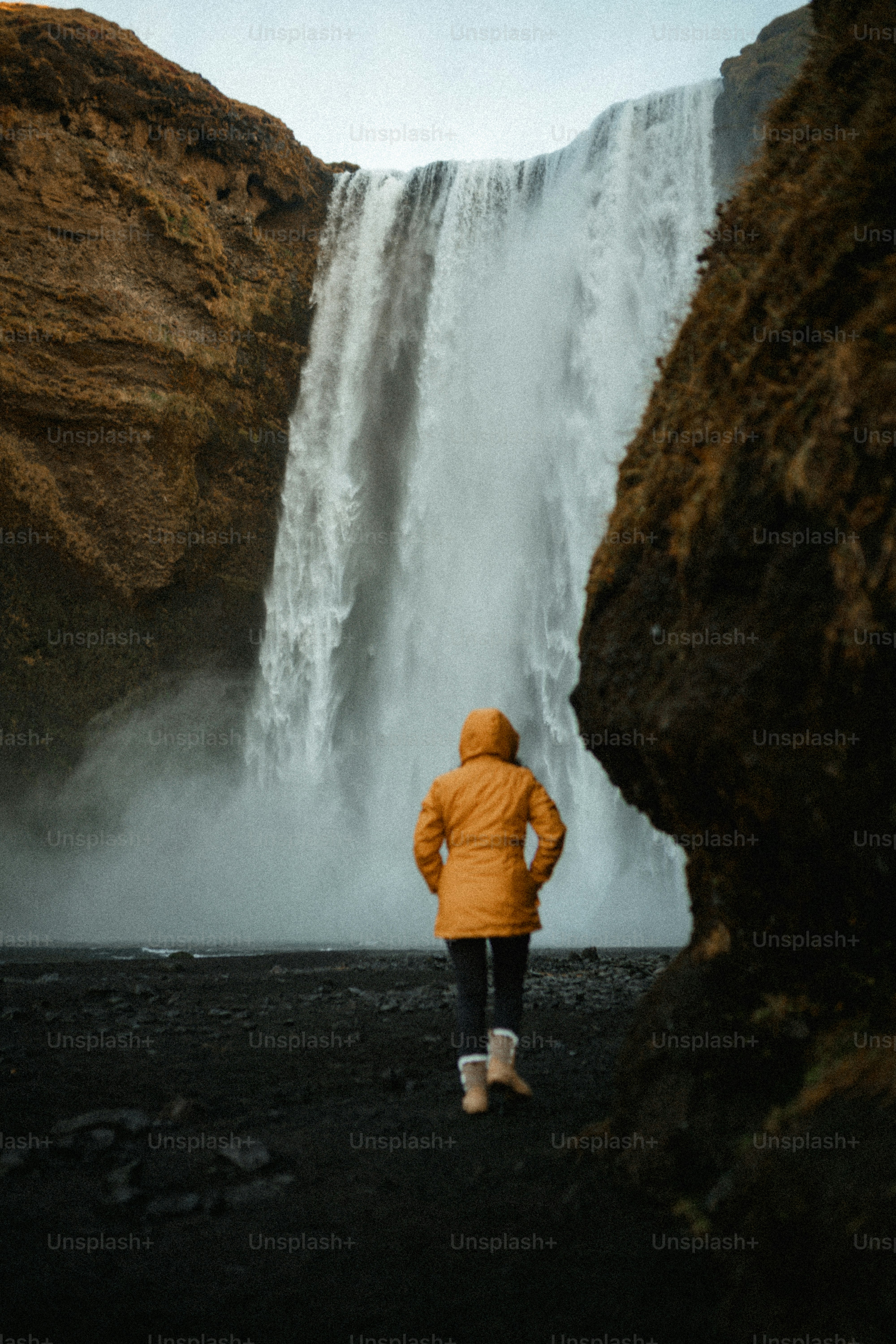 Person in yellow jacket facing a large waterfall