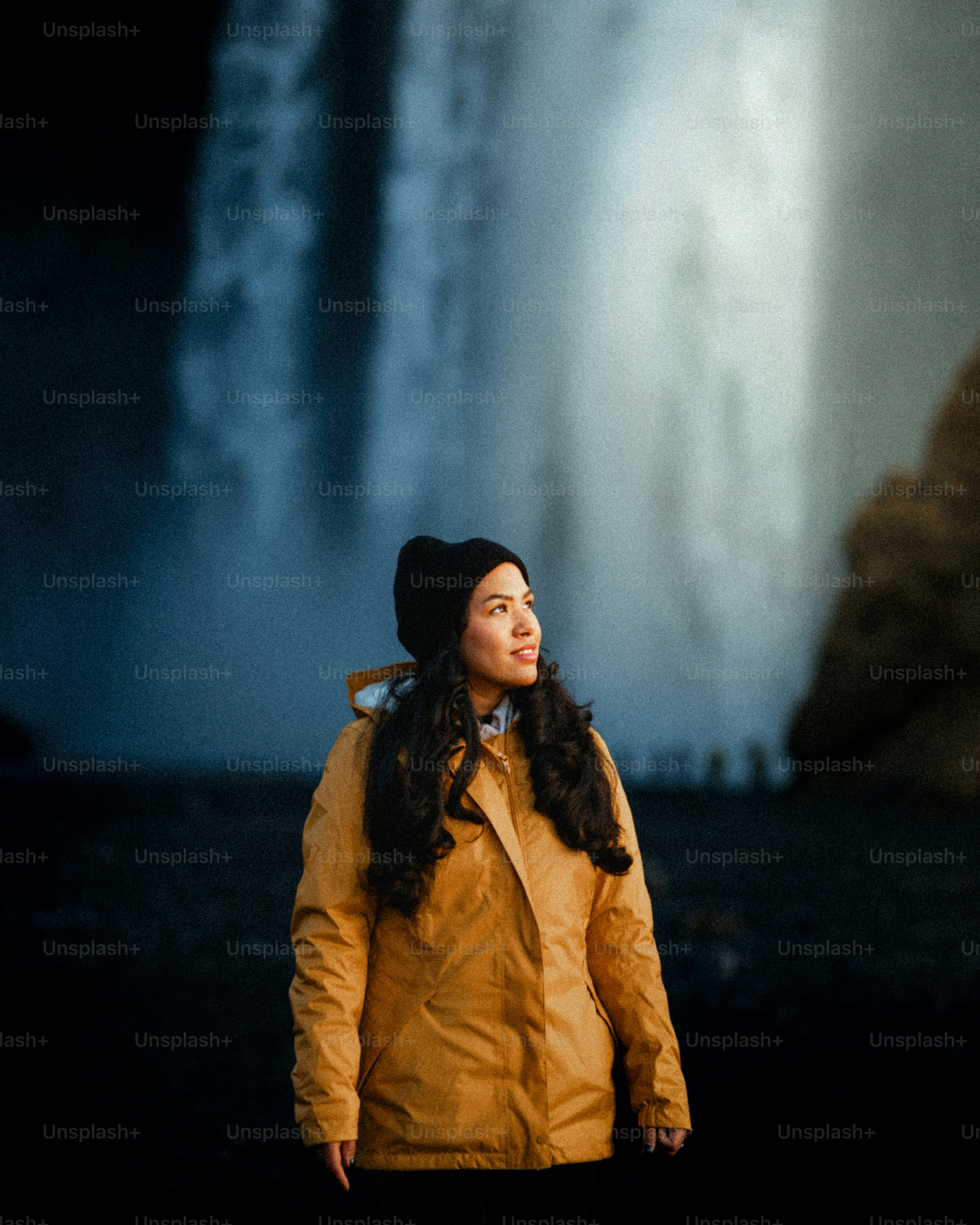 Woman in yellow jacket looking at waterfall